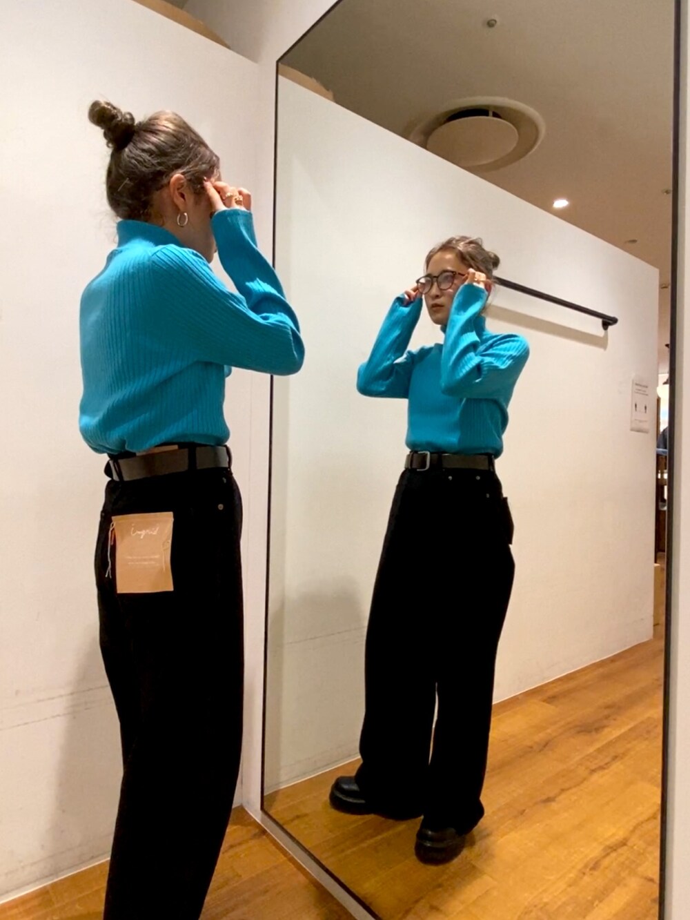 ブラック系のデニムパンツ、ブラック系のブーツ、ブルー系のニット/セーターを着用したレディースの秋コーディネートの2枚目の写真