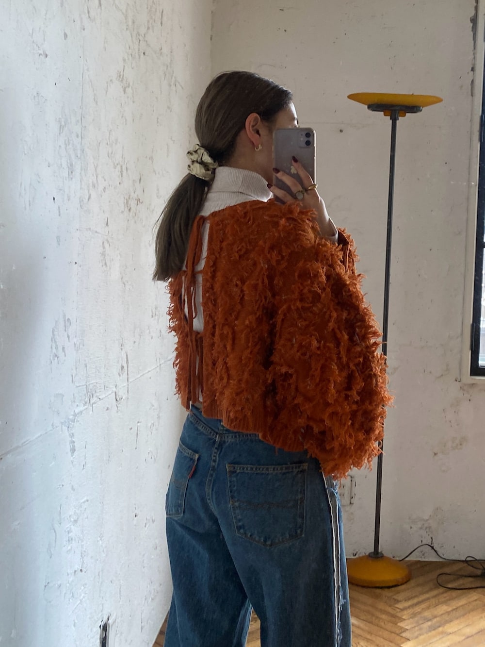 オレンジ系のニット/セーター、ホワイト系のニット/セーター、ブルー系のデニムパンツを着用したレディースの秋コーディネートの2枚目の写真