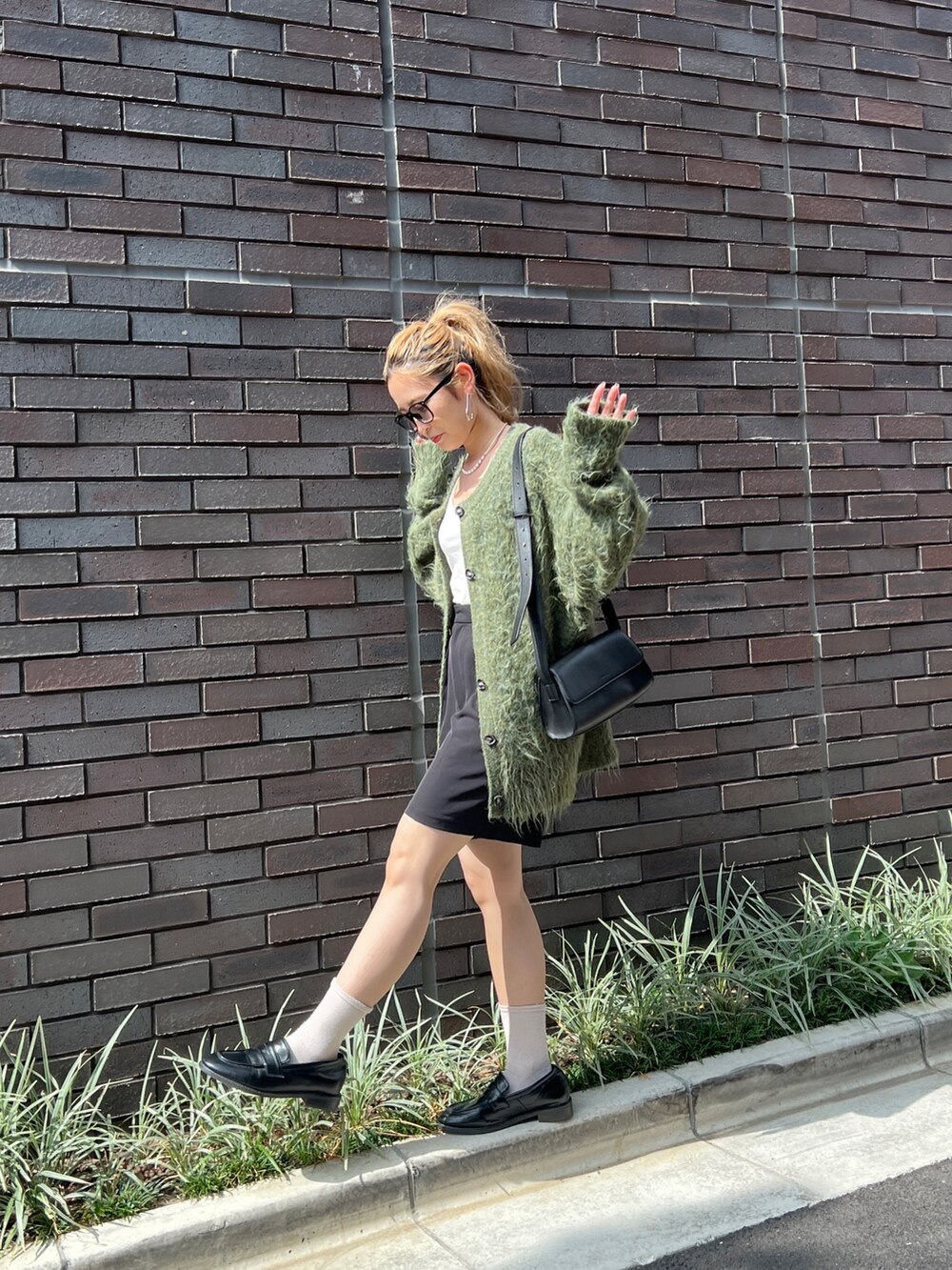 グリーン系のカーディガン/ボレロ、ブラック系のショルダーバッグ、ブラック系のローファーを着用したレディースの秋コーディネートの2枚目の写真