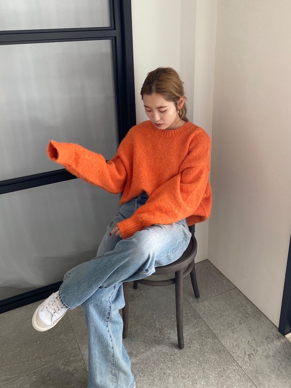 オレンジ系のニット/セーター、ブルー系のデニムパンツを着用したレディースの冬コーディネートの2枚目の写真