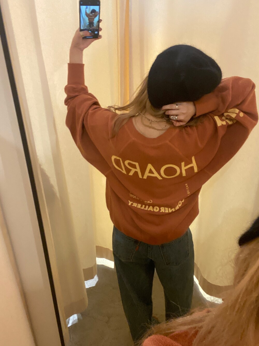 オレンジ系のスウェット、ブルー系のデニムパンツ、ブラック系のニットキャップ/ビーニーを着用したレディースの秋コーディネートの2枚目の写真