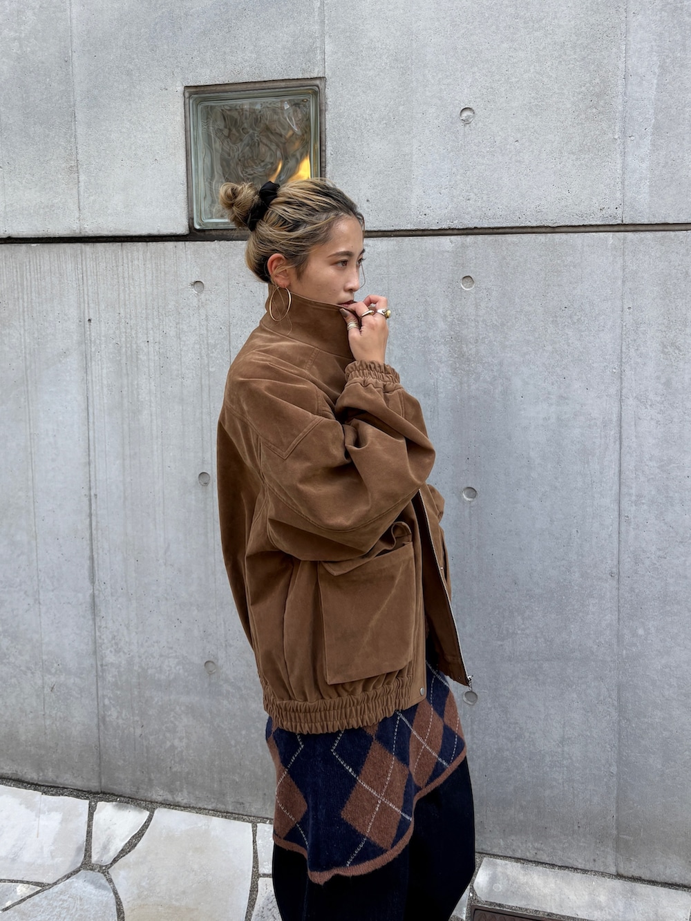 ブラウン系のブルゾン、ブラウン系のニット/セーター、ブルー系のデニムパンツを着用したレディースの秋コーディネートの4枚目の写真