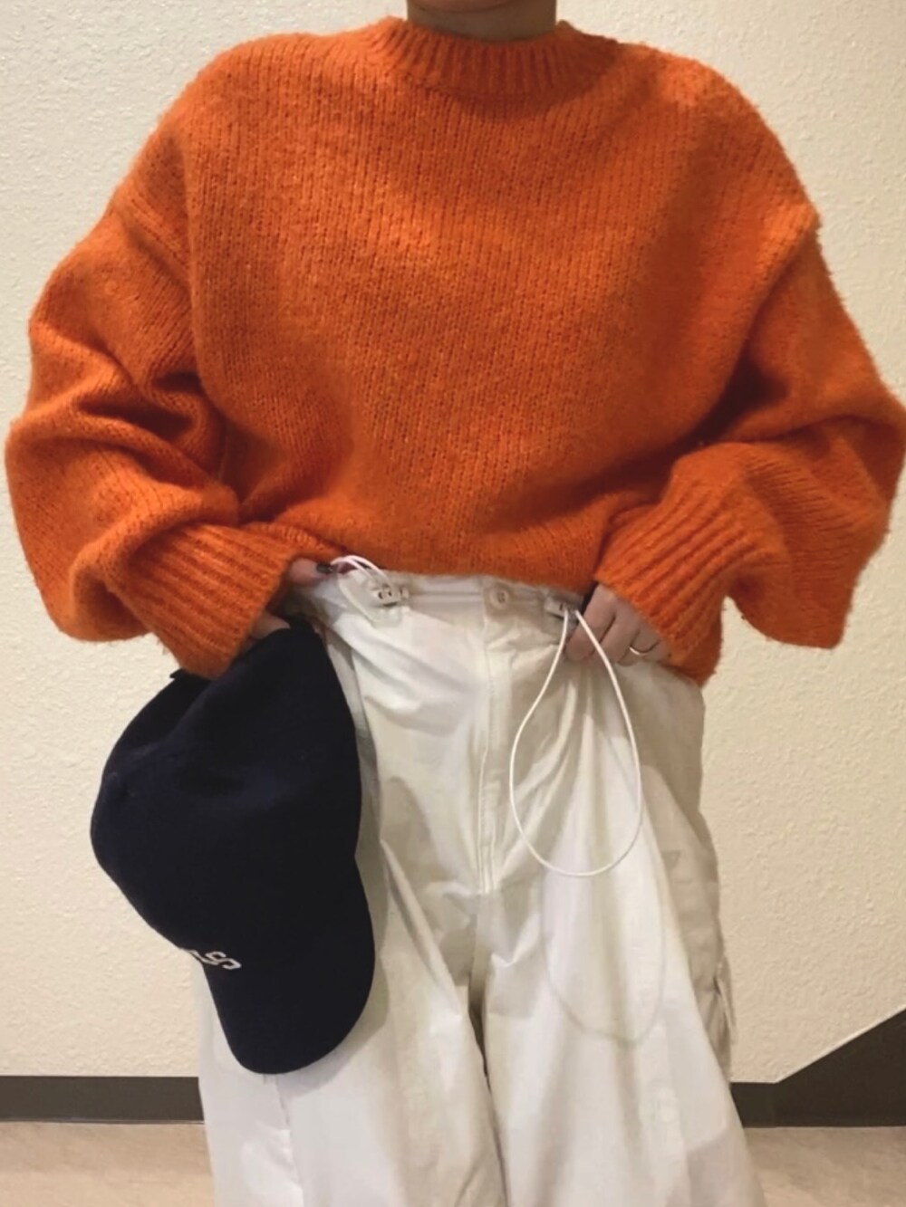 オレンジ系のニット/セーター、ホワイト系のカーゴパンツ、ブラック系のブーツを着用したレディースの冬コーディネートの5枚目の写真