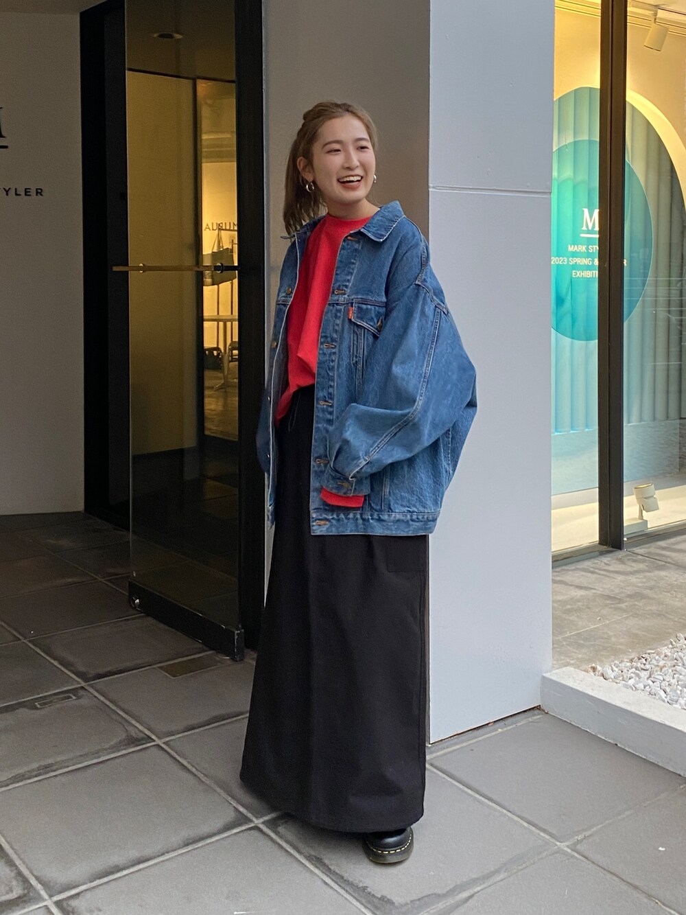 ブルー系のデニムジャケット、レッド系のスウェット、ブラック系のスカートを着用したレディースの冬コーディネートの3枚目の写真