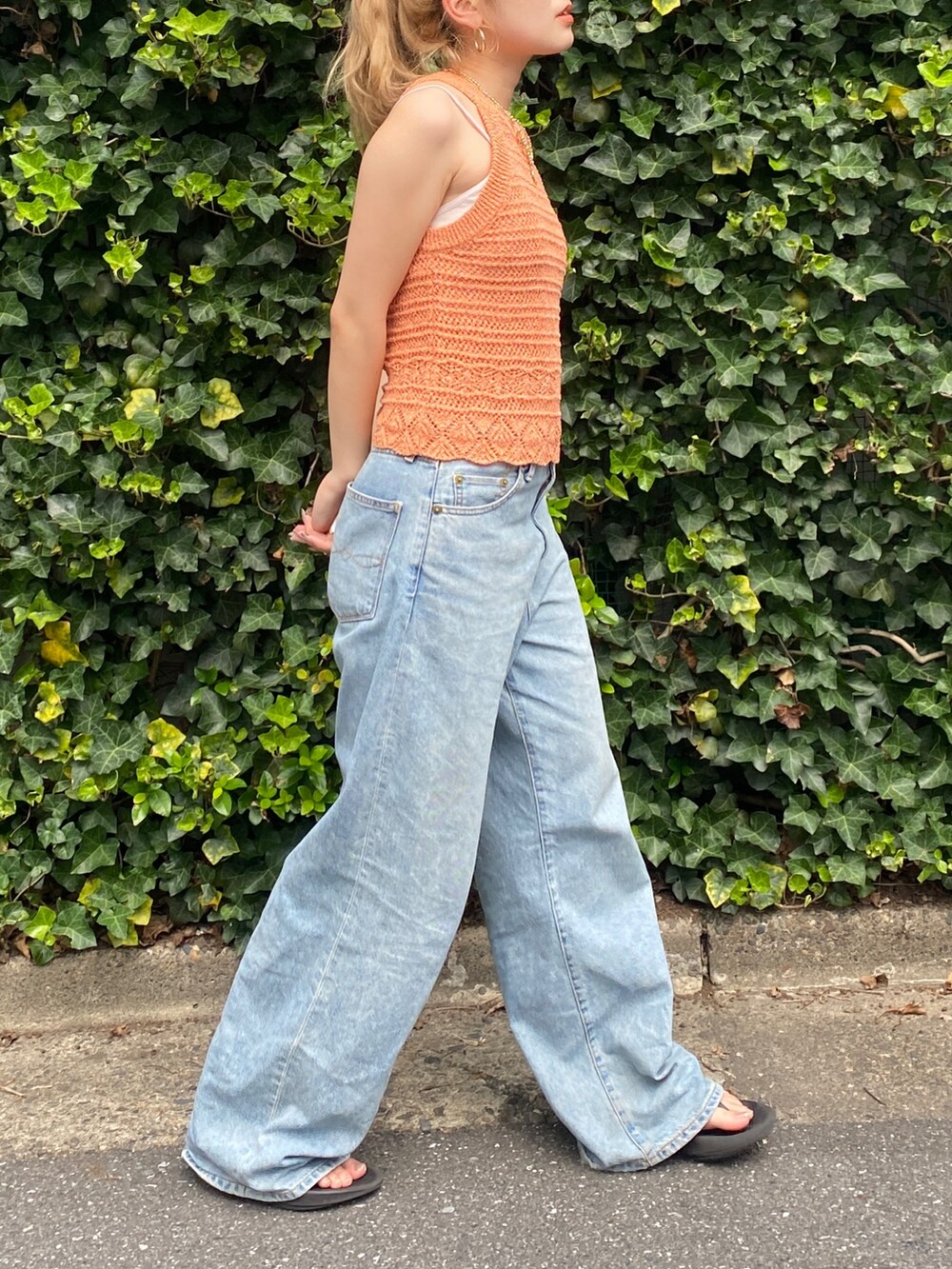 オレンジ系のニット/セーター、ブルー系のデニムパンツを着用したレディースの夏コーディネートの2枚目の写真