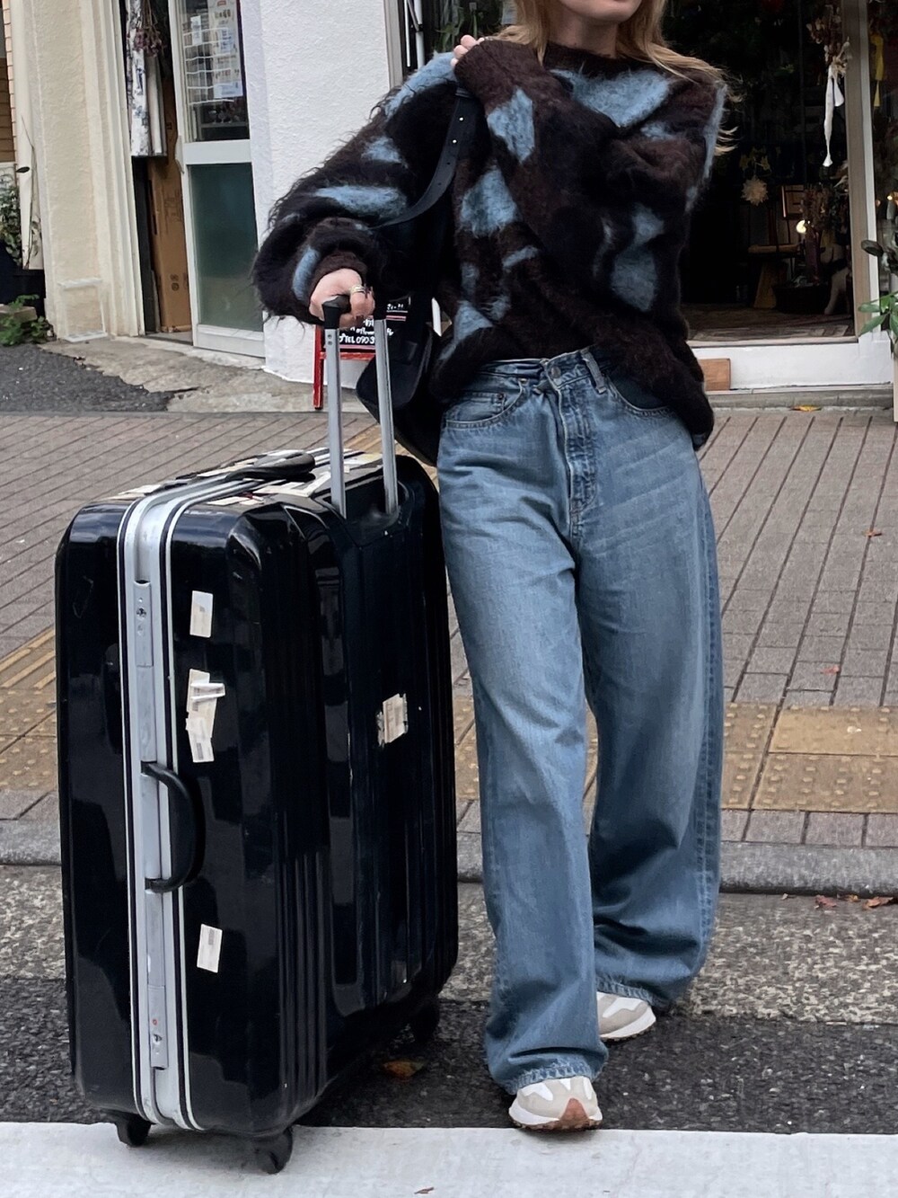 ブラウン系のニット/セーター、ブルー系のデニムパンツ、ブラック系のメガネを着用したレディースの秋コーディネートの8枚目の写真