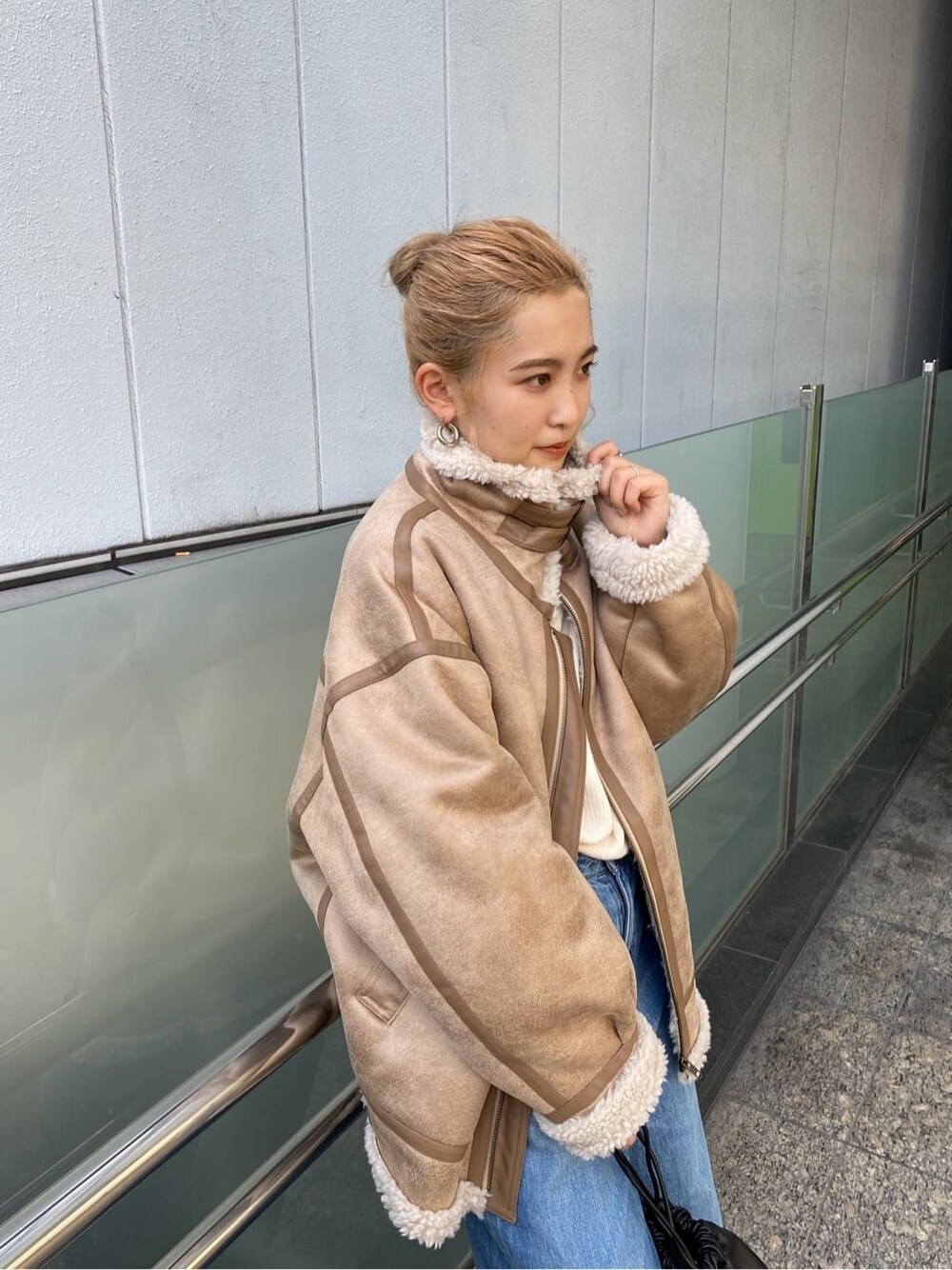 ブルー系のデニムパンツ、ブラック系のブーツ、ブラック系のハンドバッグを着用したレディースの秋コーディネートの6枚目の写真