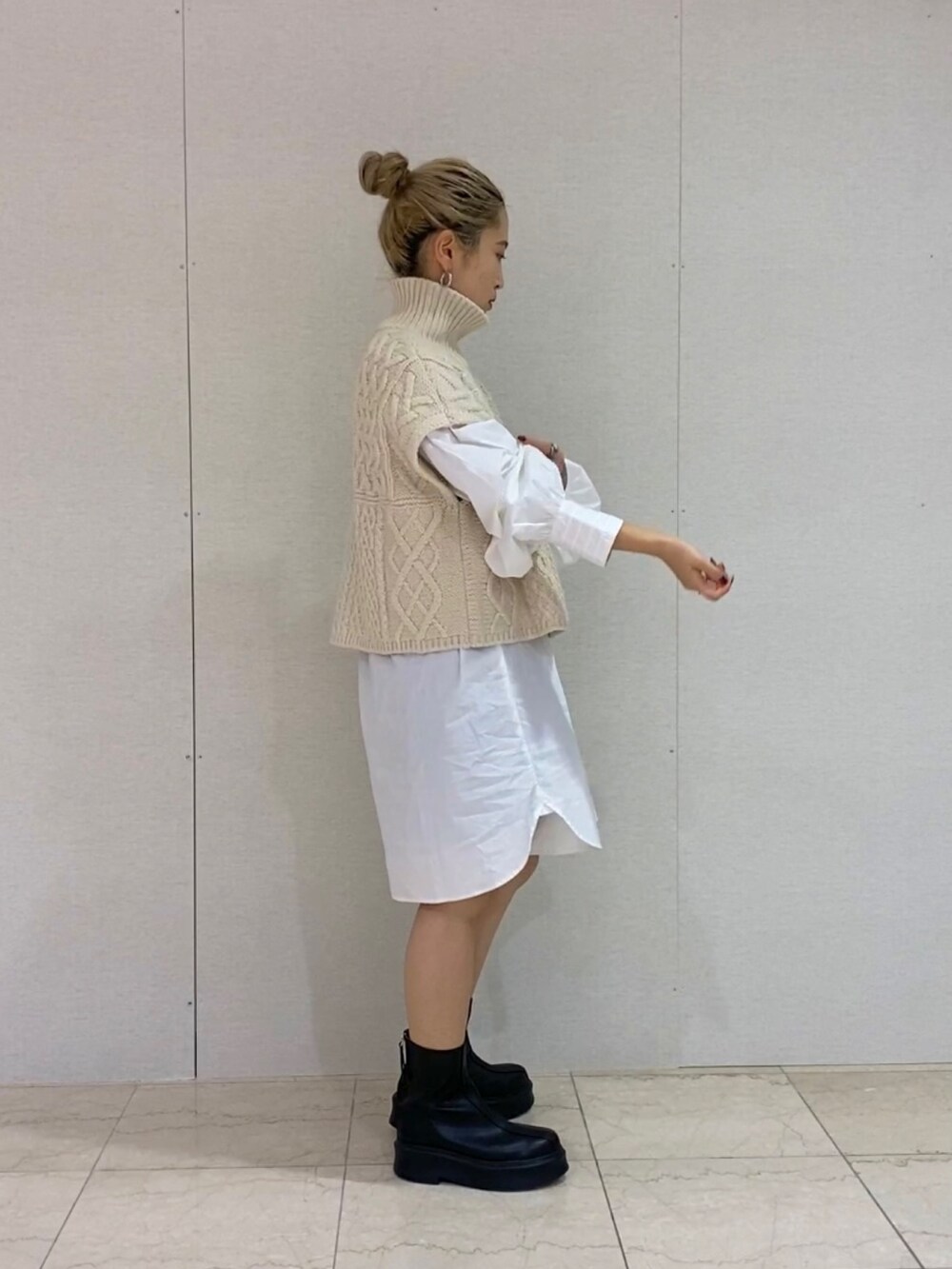 ホワイト系のシャツ/ブラウス、ホワイト系のニット/セーター、ブラック系のブーツを着用したレディースの秋コーディネートの2枚目の写真