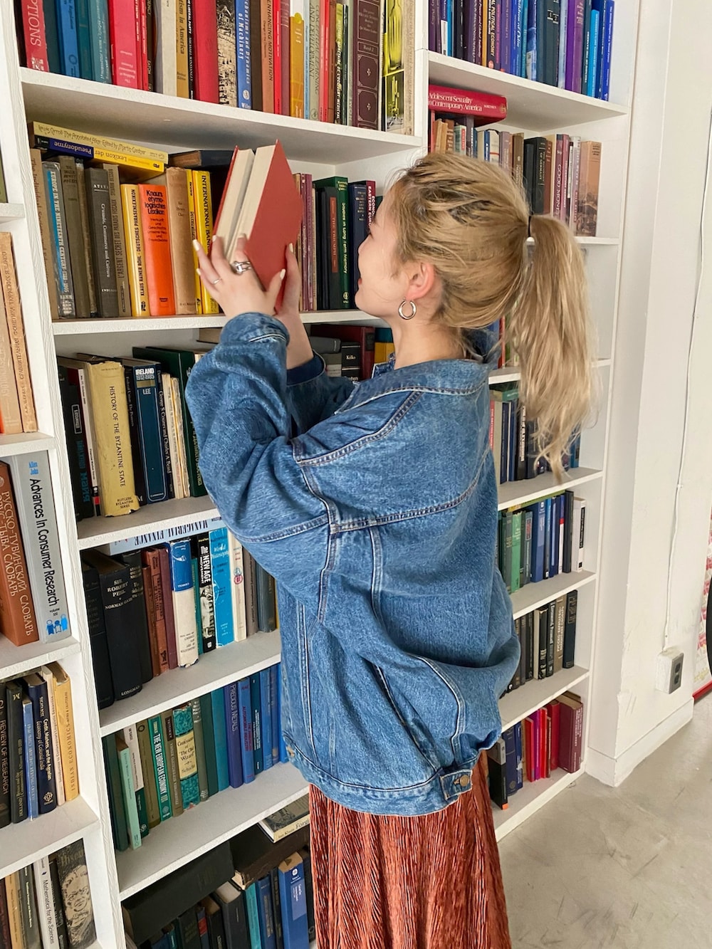 ブルー系のデニムジャケット、オレンジ系のワンピース、ブラック系のブーツを着用したレディースの秋コーディネートの3枚目の写真