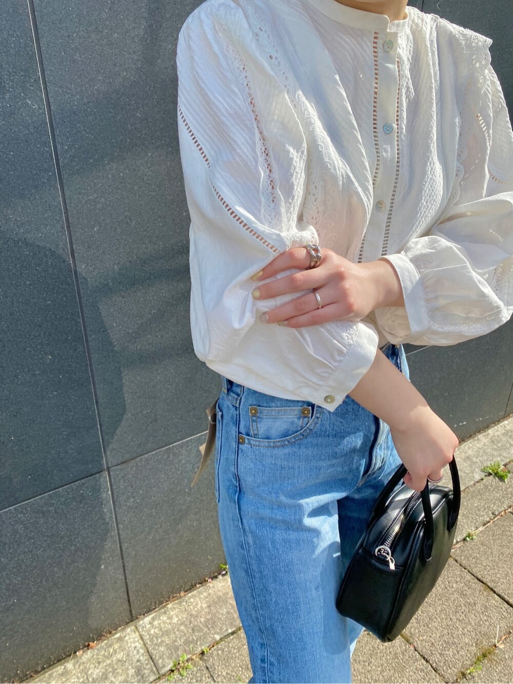 ブラック系のハンドバッグ、ブラック系のパンプス、ブルー系のデニムパンツを着用したレディースの春コーディネートの3枚目の写真