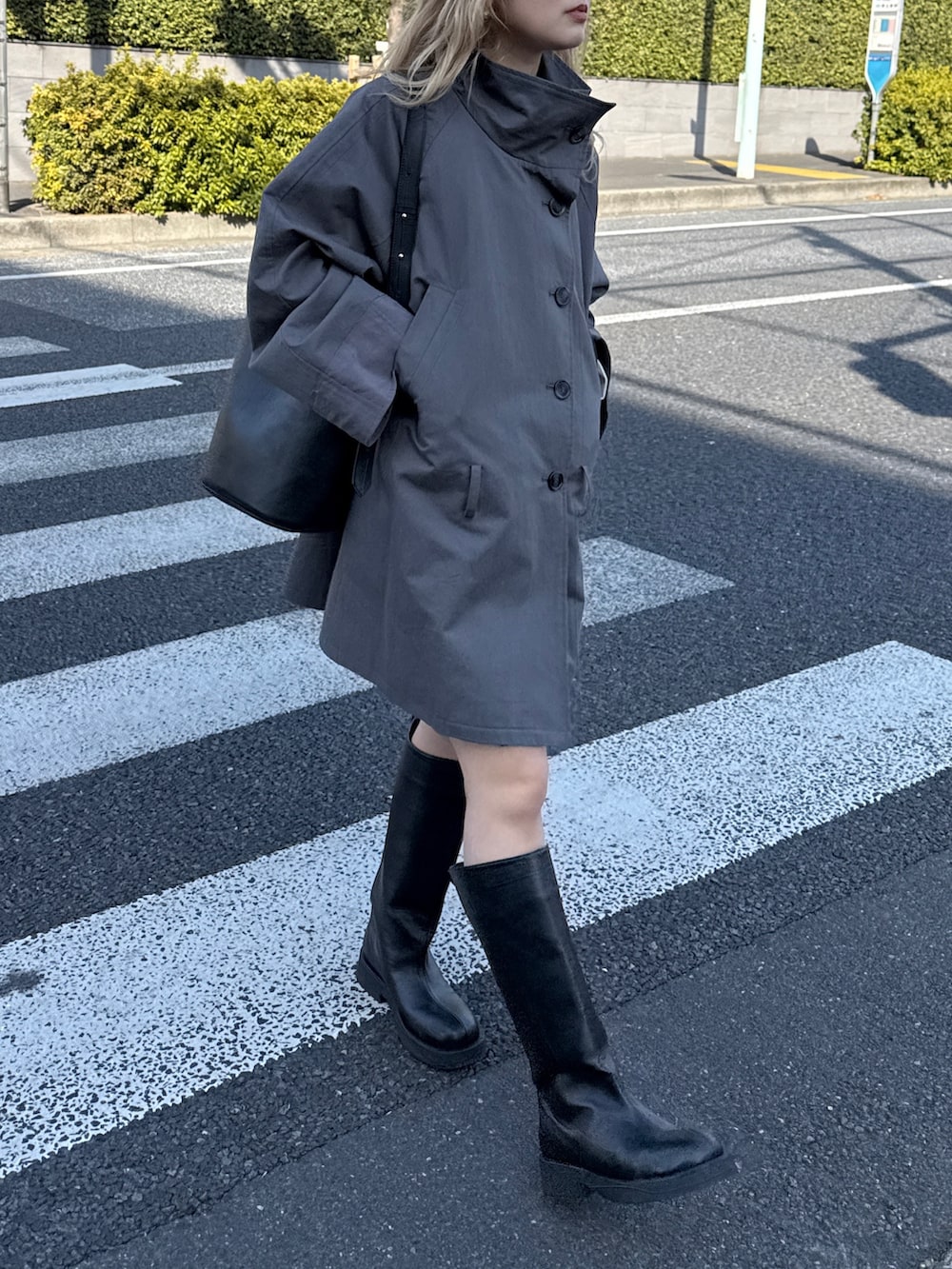 グレー系のトレンチコート、ブラック系のブーツを着用したレディースの冬コーディネートの2枚目の写真