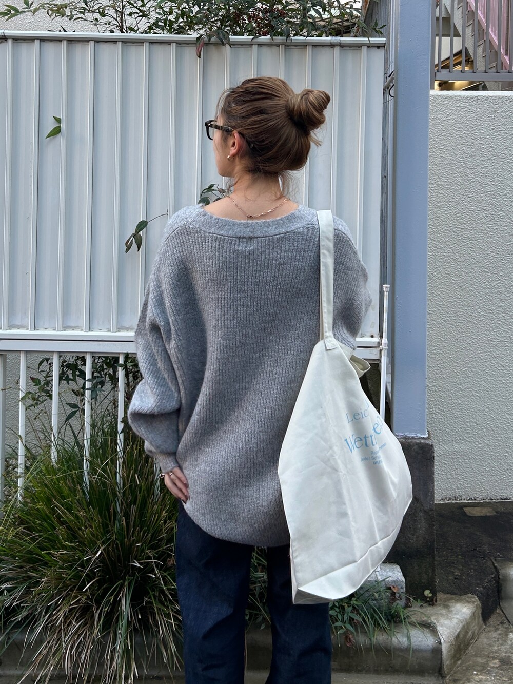 ブラック系のブルゾン、グレー系のカーディガン/ボレロ、ブルー系のデニムパンツを着用したレディースの冬コーディネートの8枚目の写真