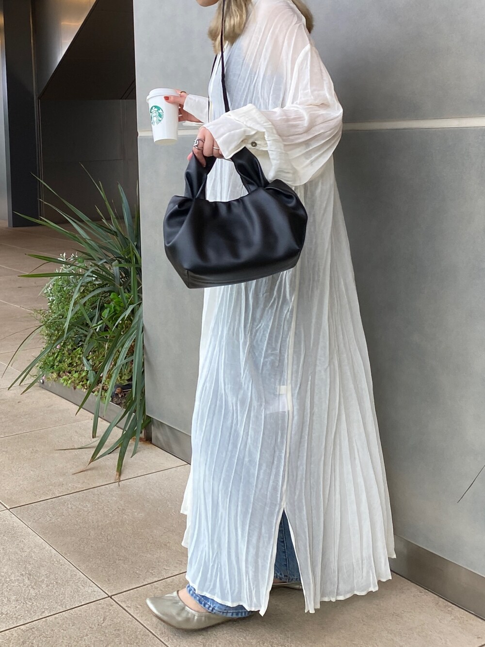 ホワイト系のワンピース、ブルー系のデニムパンツ、ブラック系のハンドバッグを着用したレディースの春コーディネートの3枚目の写真