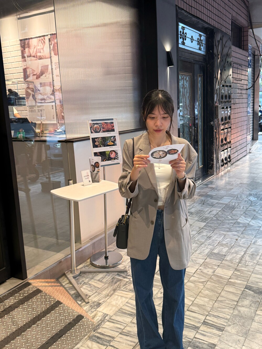 ホワイト系のキャミソール、ベージュ系のチェスターコート、ブルー系のデニムパンツを着用したレディースの秋コーディネートの3枚目の写真