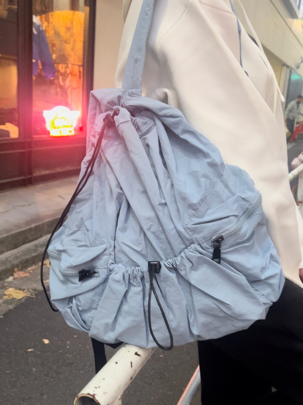 ブルー系のバックパック/リュック、ホワイト系のパーカー、ブラック系のスニーカーを着用したレディースの秋コーディネートの2枚目の写真