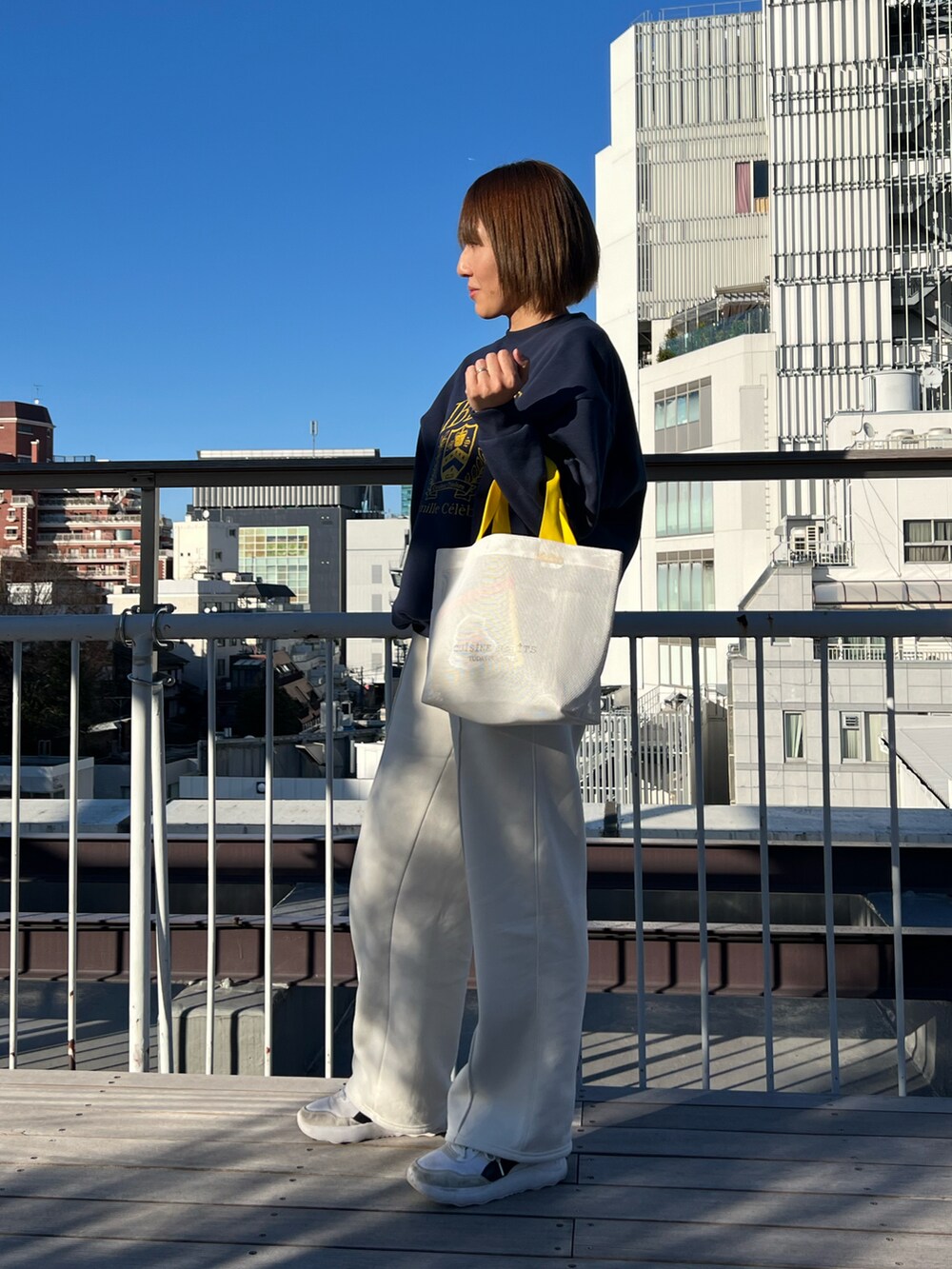 ホワイト系のトートバッグ、ホワイト系のスニーカー、ブルー系のポーチを着用したレディースの春コーディネートの2枚目の写真