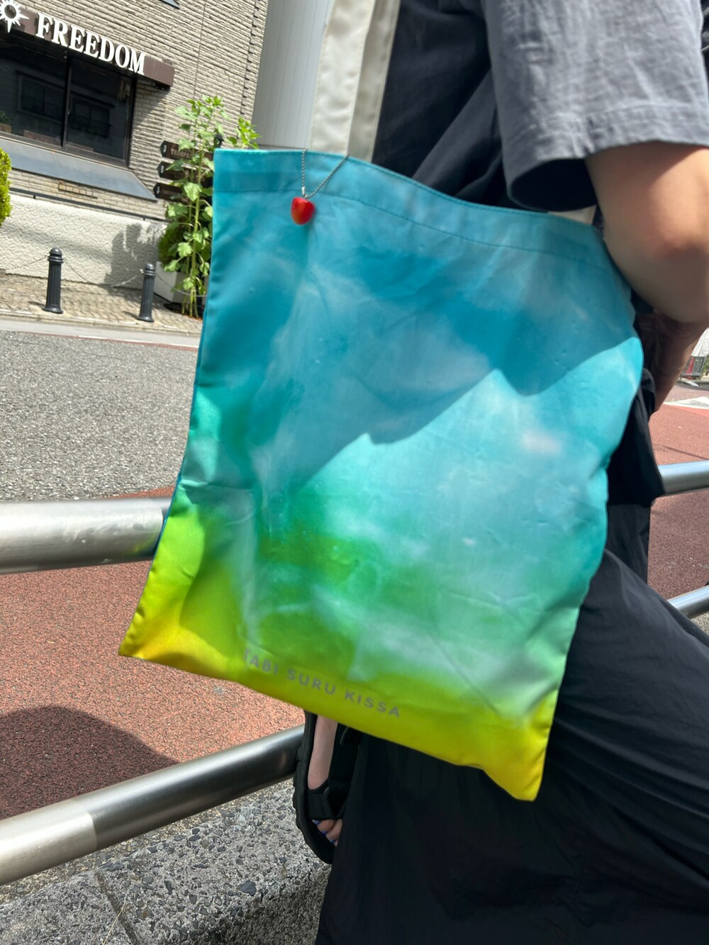 ブルー系のトートバッグ、ブルー系のパンツを着用したレディースの夏コーディネートの2枚目の写真