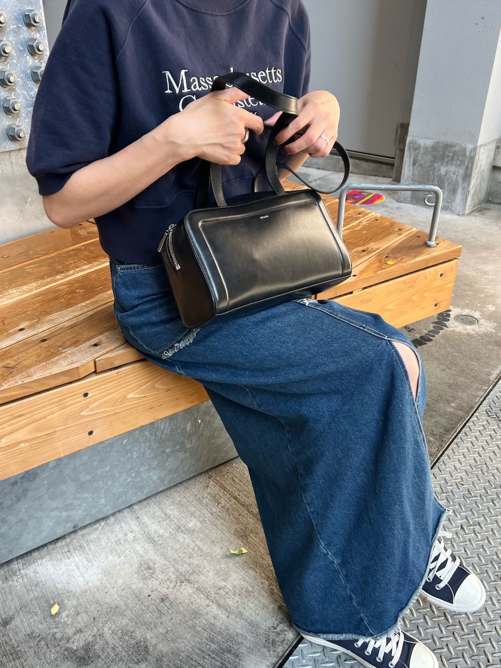 ブラック系のボストンバッグ、ブルー系の折りたたみ傘、ブラウン系のポーチを着用したレディースの夏コーディネートの2枚目の写真