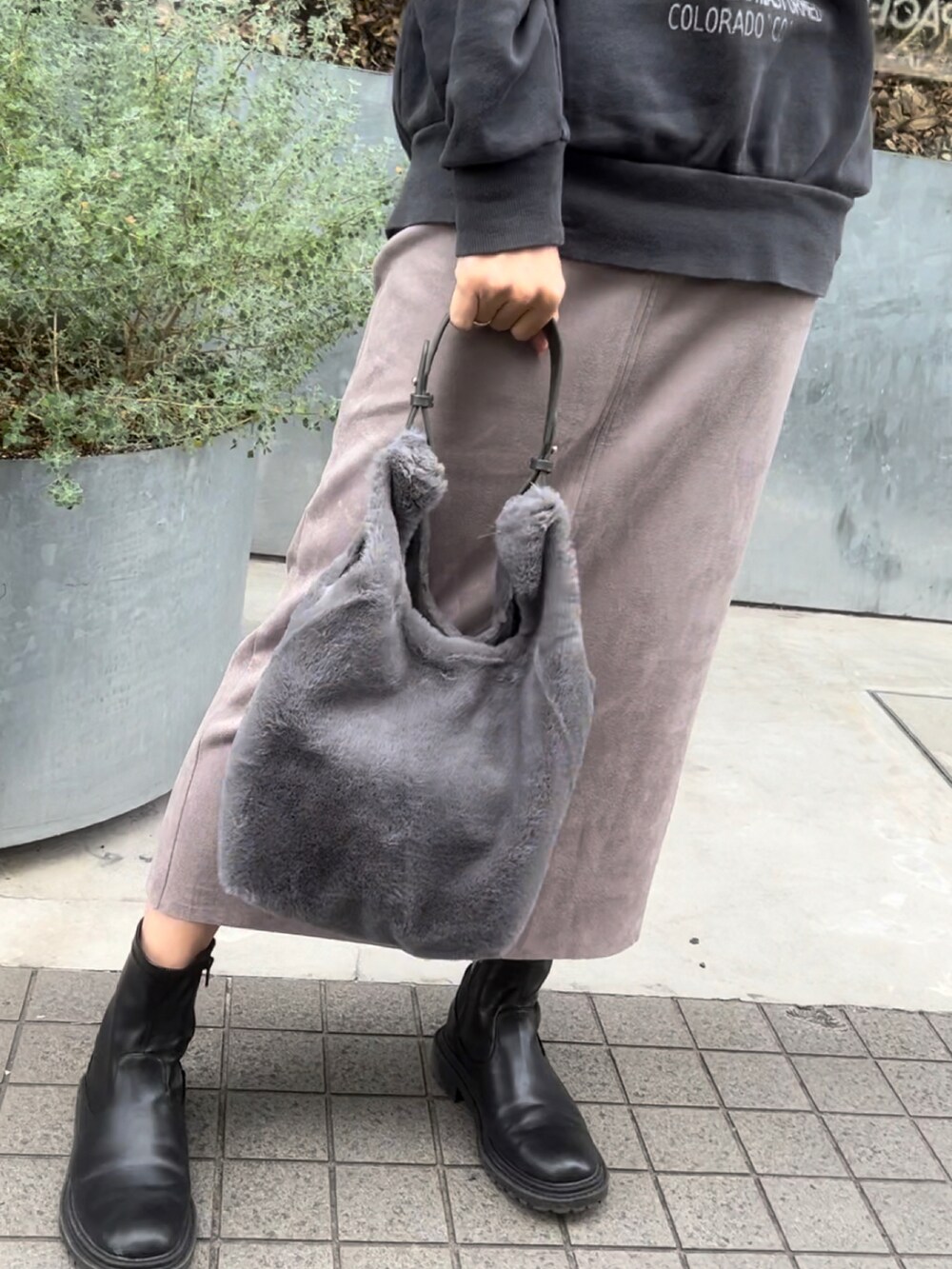 グレー系のトートバッグ、ブラック系のブーツ、ピンク系のスカートを着用したレディースの冬コーディネートの2枚目の写真