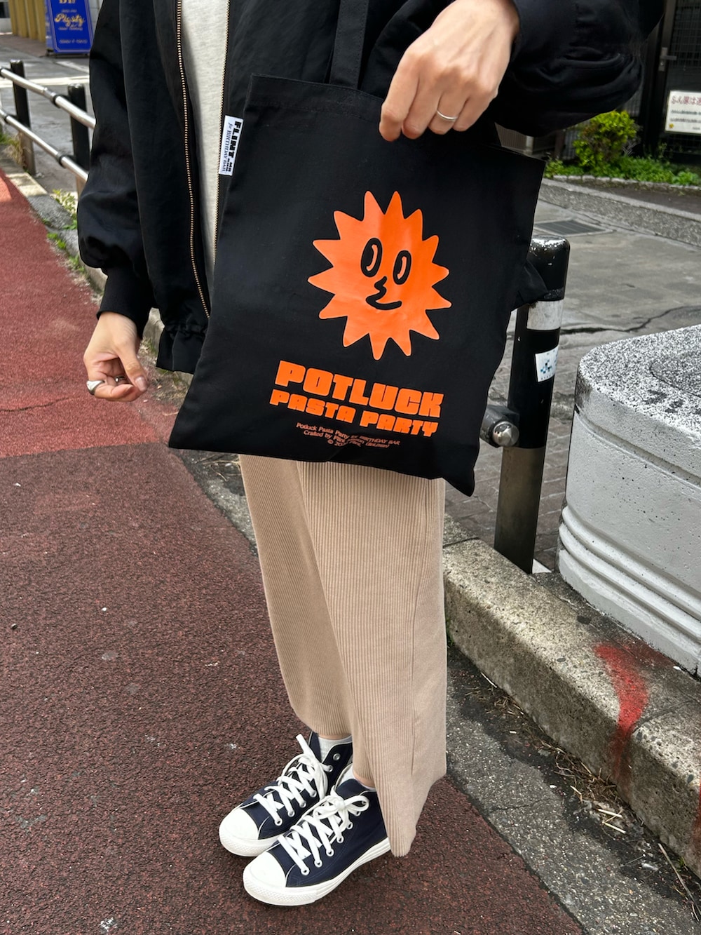 ベージュ系のトートバッグ、ブルー系のスニーカー、ブラック系のその他アウターを着用したレディースの春コーディネートの2枚目の写真