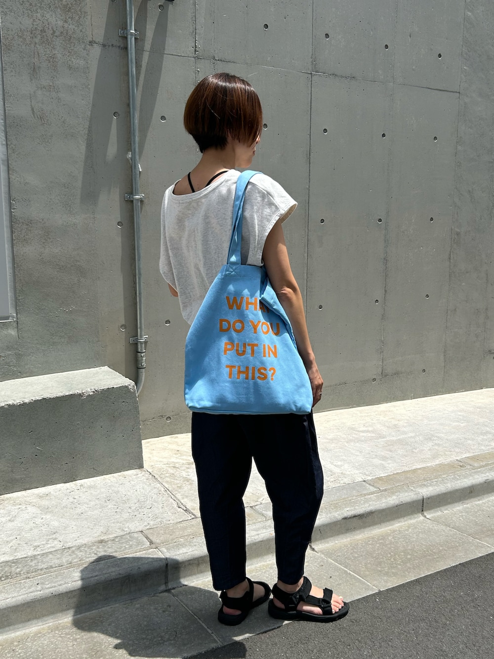 ブルー系のトートバッグを着用したレディースの夏コーディネートの2枚目の写真