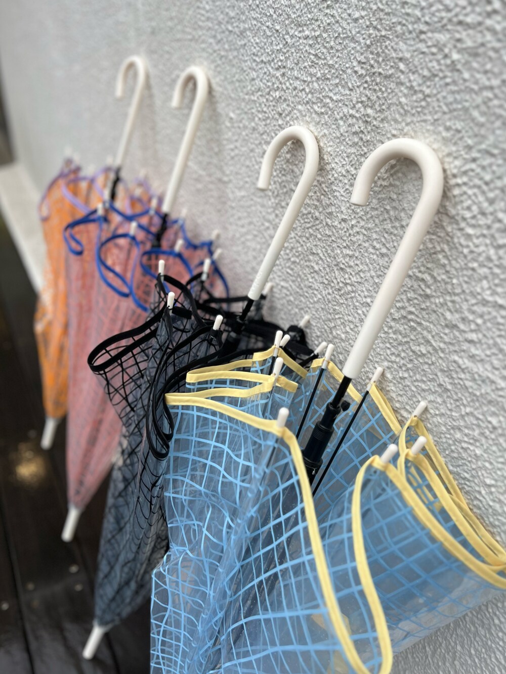 ブラック系のスカート、ホワイト系のスニーカー、ブルー系の長傘を着用したレディースの春コーディネートの3枚目の写真