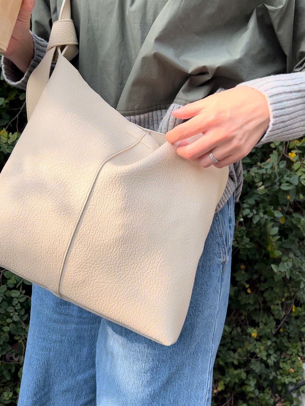 シルバー系のショルダーバッグ、グリーン系のニット/セーター、ブルー系のデニムパンツを着用したレディースの春コーディネートの2枚目の写真