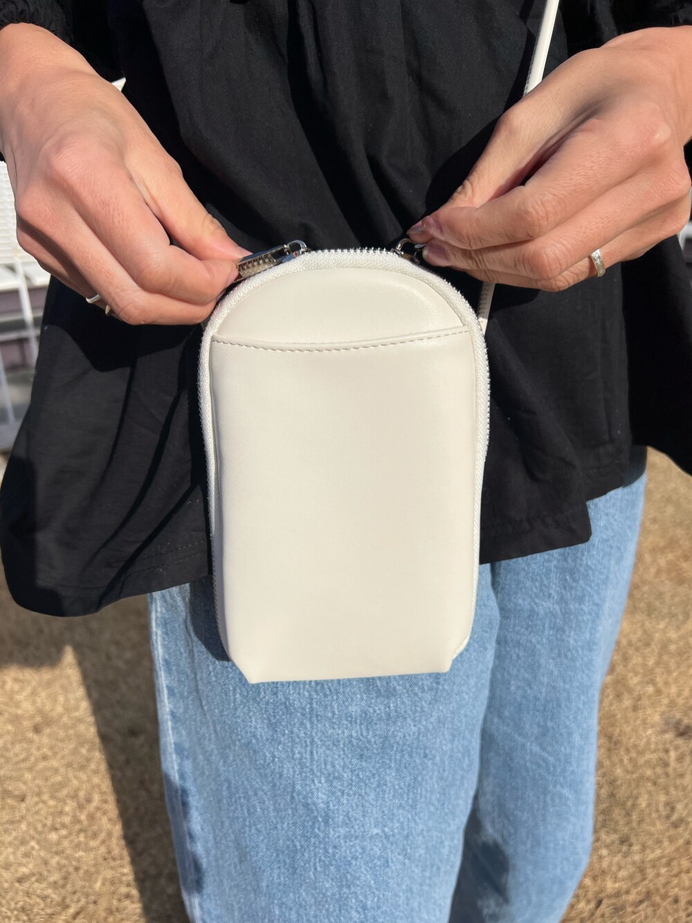 ブルー系のデニムパンツ、ホワイト系のショルダーバッグ、ブラック系のトップスを着用したレディースの冬コーディネートの2枚目の写真