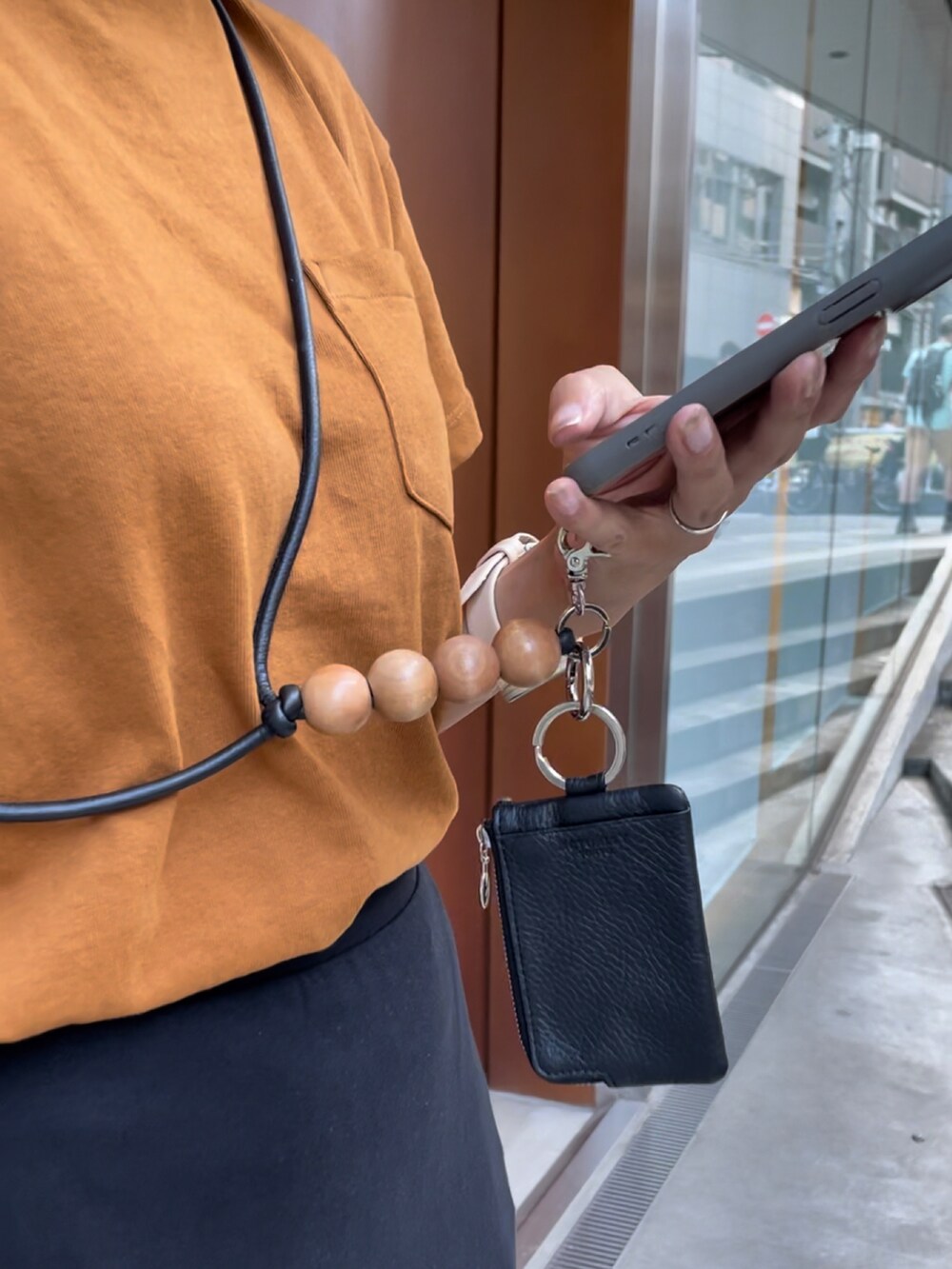 ブラウン系のTシャツ/カットソー、ブラック系のスカート、ブラック系のスマホグッズを着用したレディースの秋コーディネートの2枚目の写真