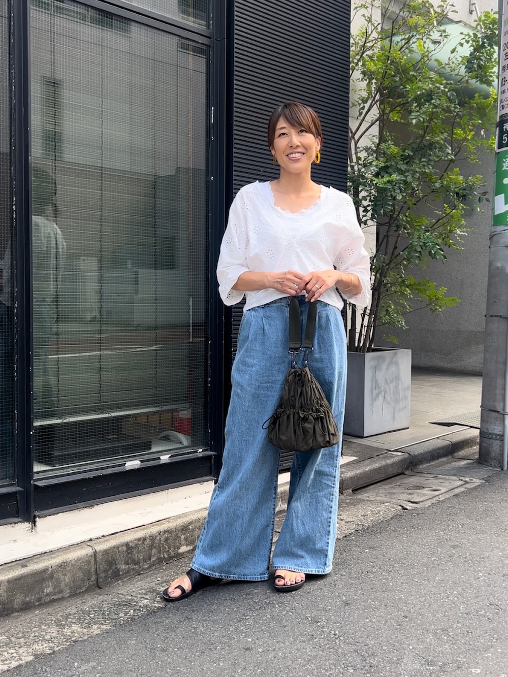 ブラック系のトートバッグ、ブルー系のデニムパンツ、ホワイト系のトップスを着用したレディースの秋コーディネートの2枚目の写真