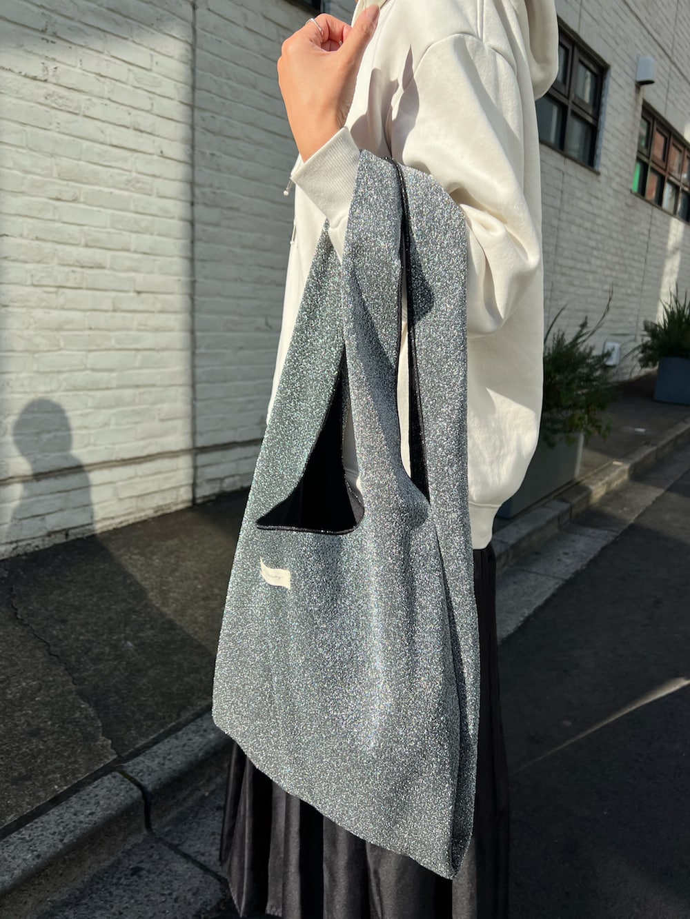 シルバー系のトートバッグ、ブラック系のスカート、ブラック系のブーツを着用したレディースの冬コーディネートの2枚目の写真