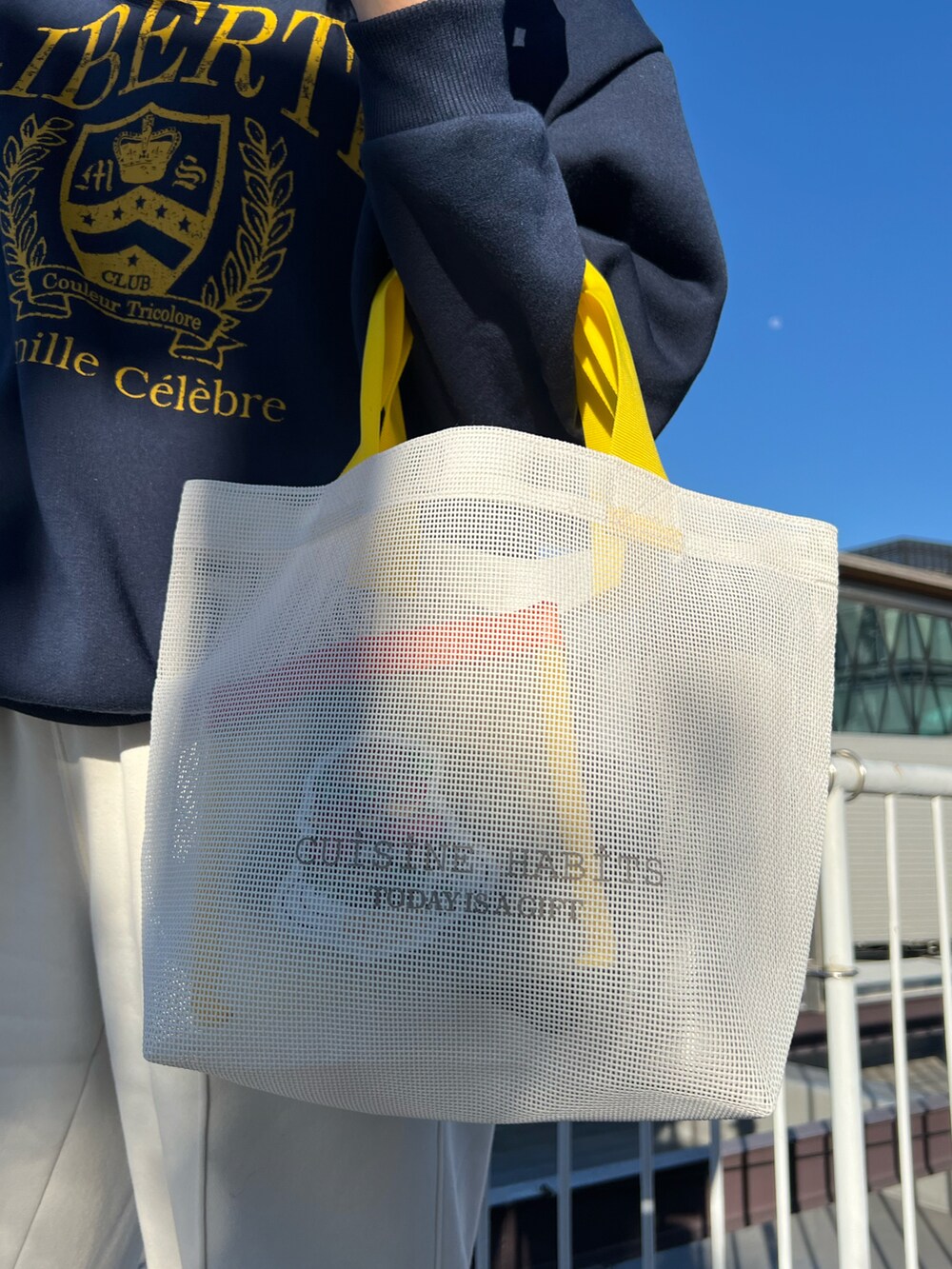 ホワイト系のトートバッグ、ホワイト系のスニーカー、ブルー系のポーチを着用したレディースの春コーディネートの3枚目の写真