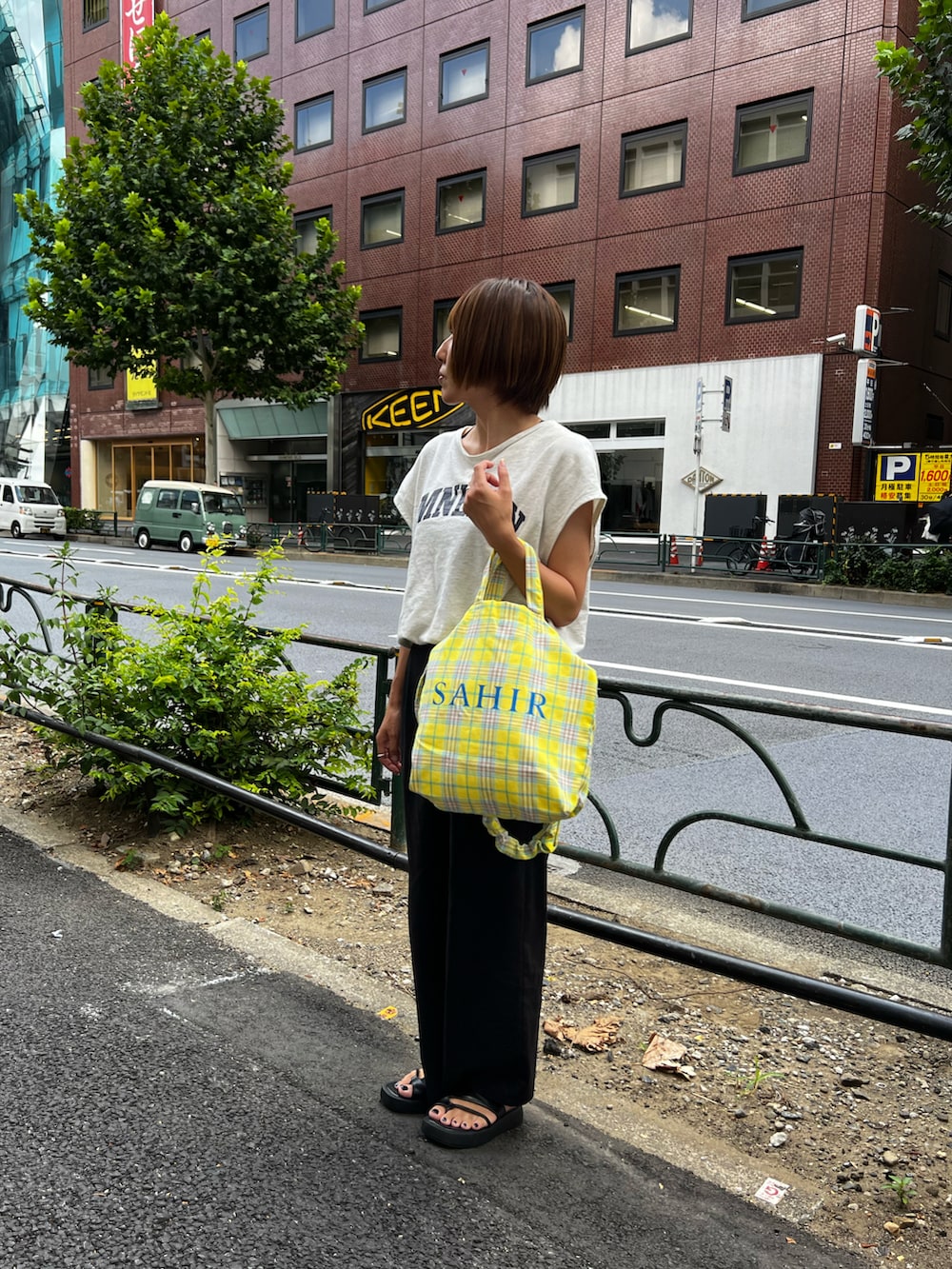 イエロー系のトートバッグ、ブラック系のその他パンツ、ホワイト系のTシャツ/カットソーを着用したレディースの夏コーディネートの2枚目の写真