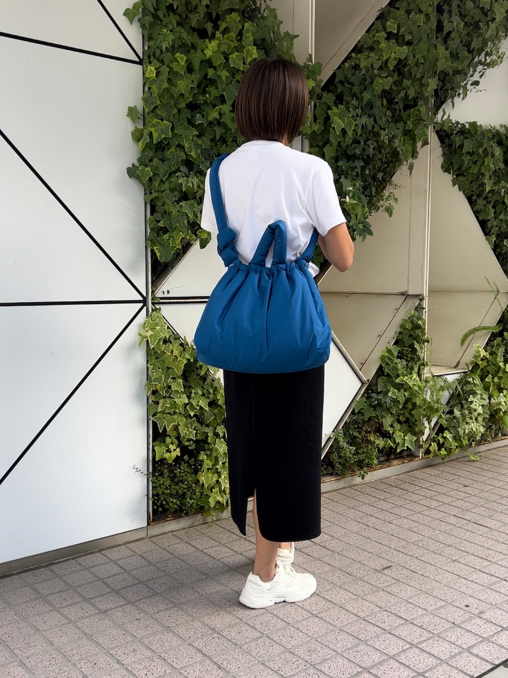 ホワイト系のTシャツ/カットソー、ブラック系のスカート、ホワイト系のスニーカーを着用したレディースの秋コーディネートの2枚目の写真