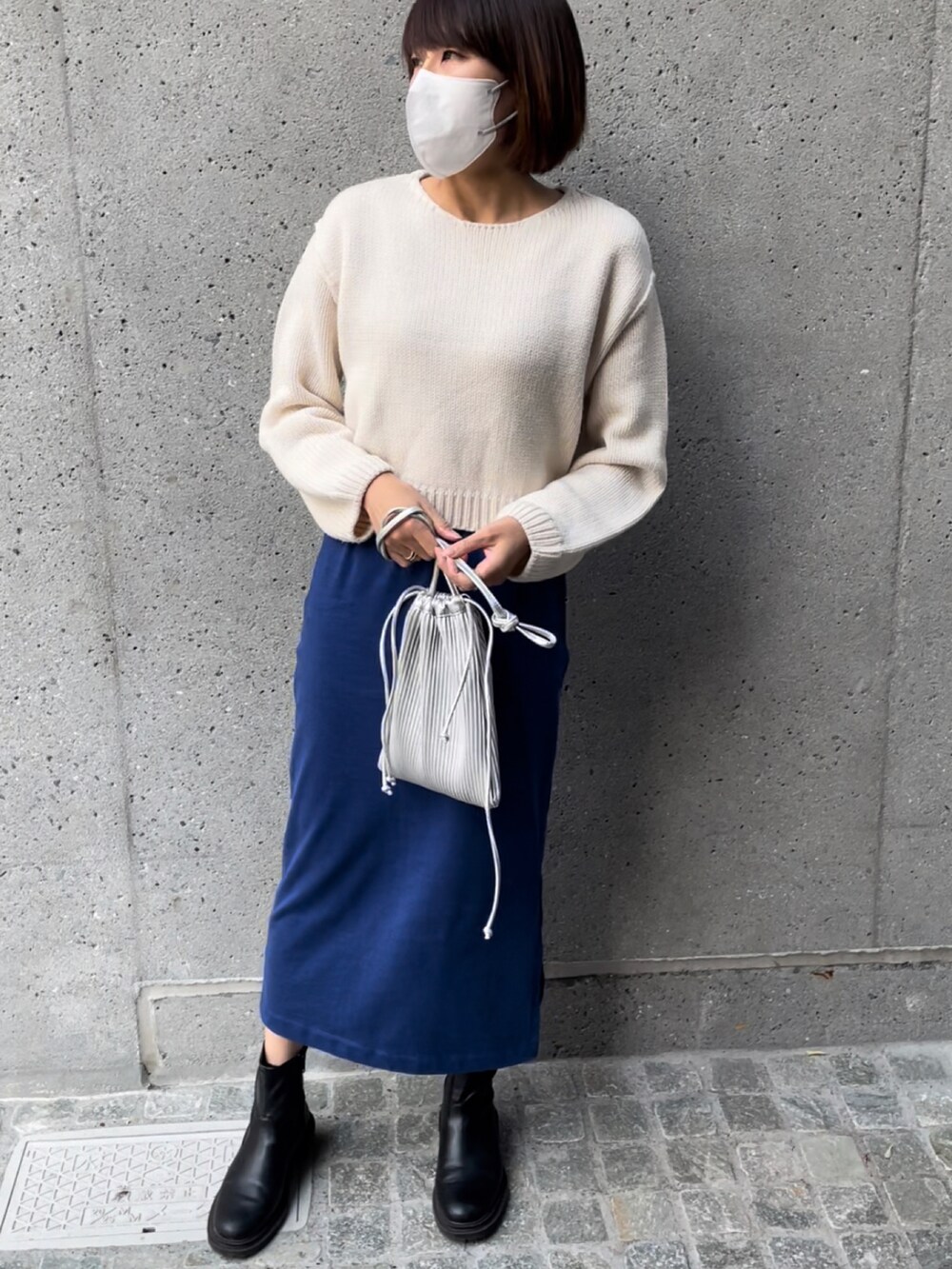 シルバー系のショルダーバッグ、ホワイト系のニット/セーター、ブルー系のスカートを着用したレディースの秋コーディネートの2枚目の写真