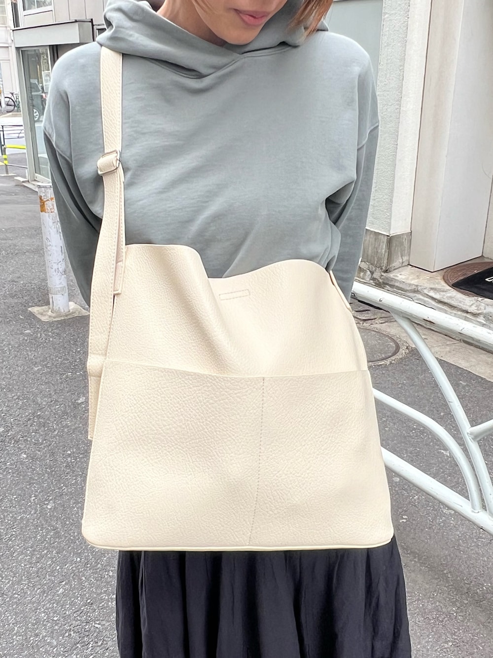 ホワイト系のショルダーバッグ、グリーン系のパーカー、ブラック系のスカートを着用したレディースの春コーディネートの2枚目の写真