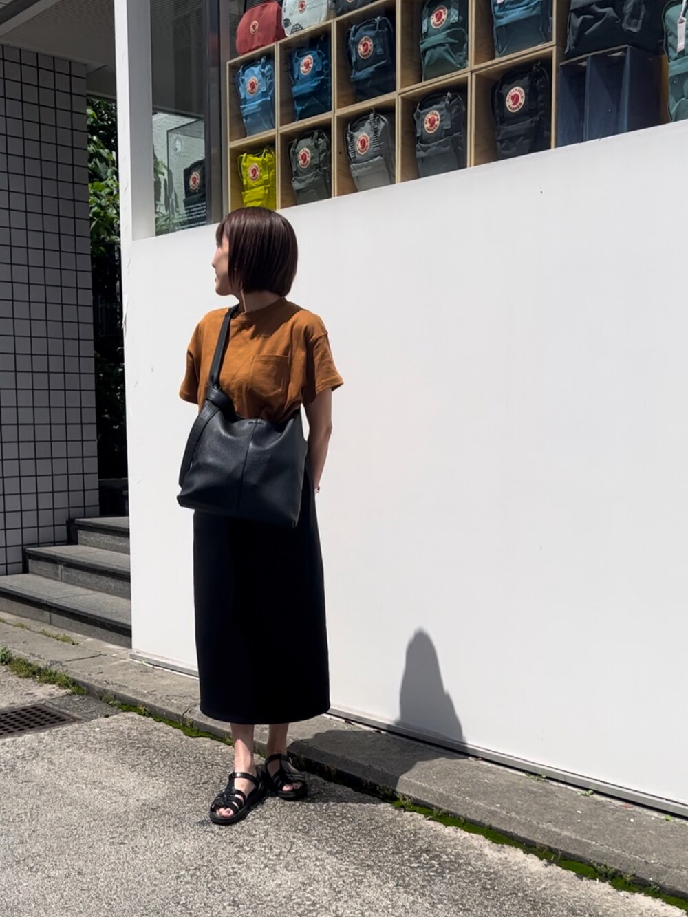 ブラウン系のTシャツ/カットソー、ブラック系のショルダーバッグ、ブラック系のスカートを着用したレディースの夏コーディネートの2枚目の写真