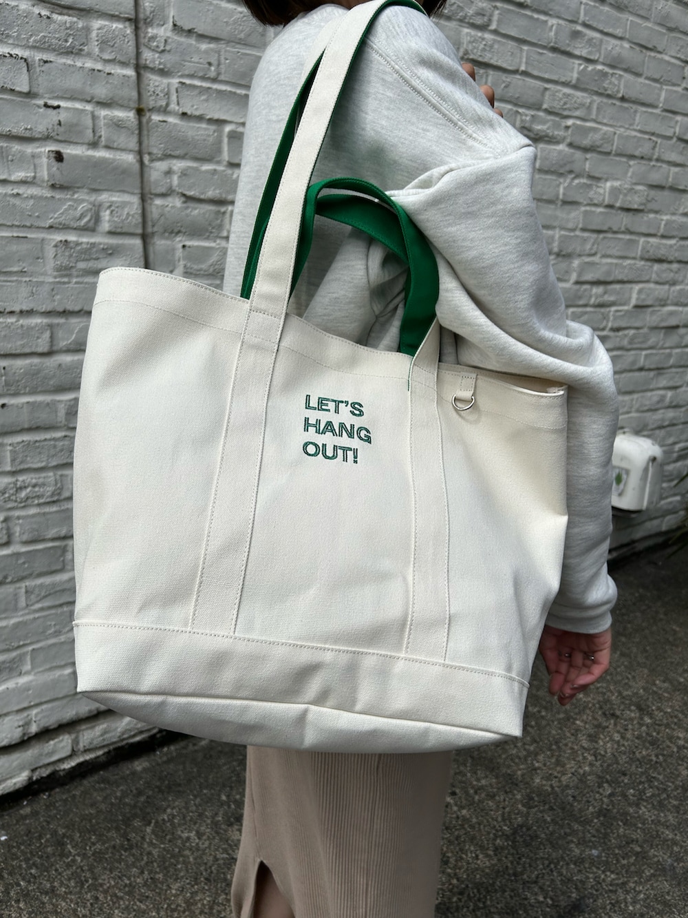 ホワイト系のトートバッグ、ブルー系のスニーカー、ホワイト系のスウェットを着用したレディースの春コーディネートの2枚目の写真