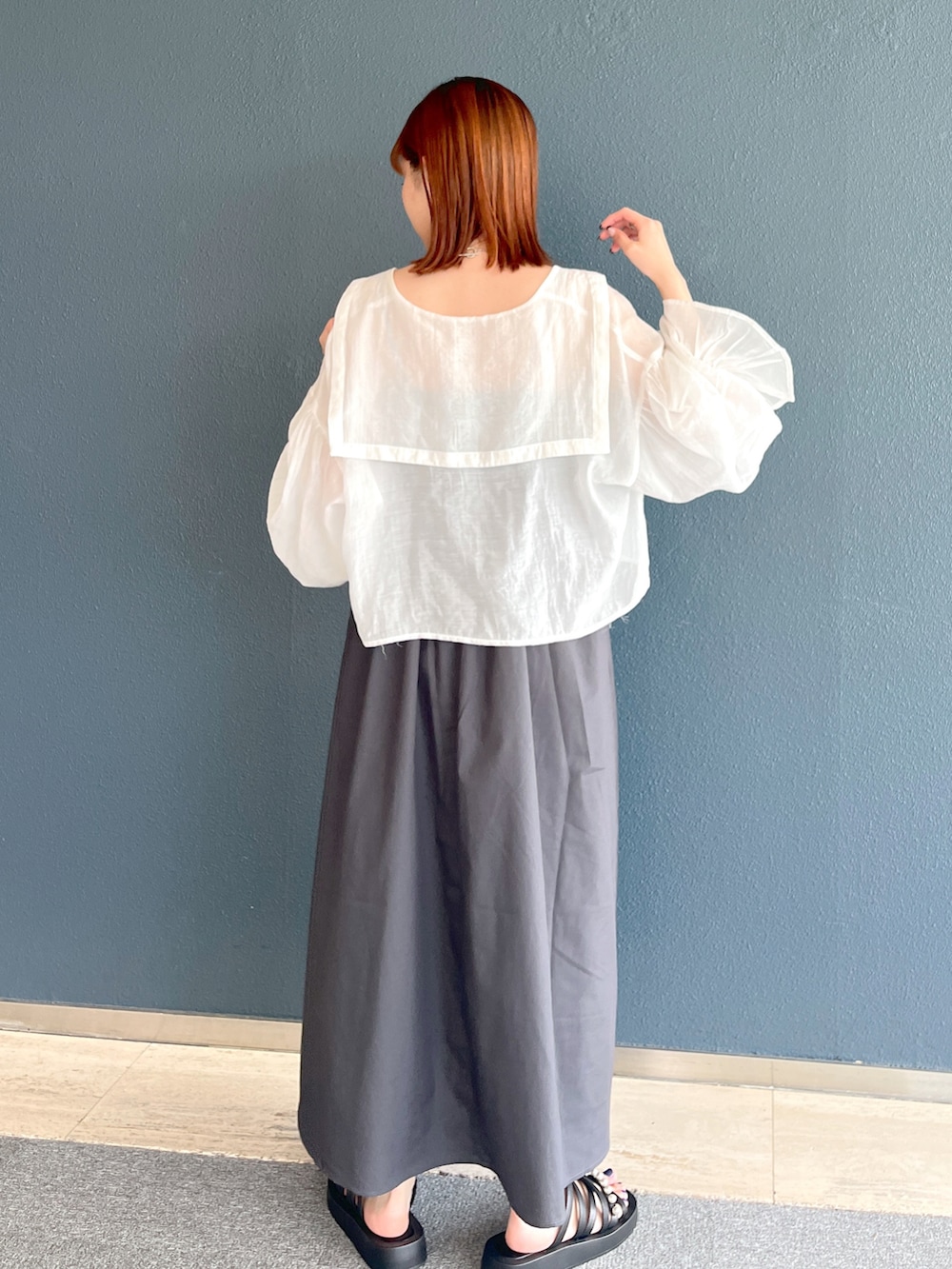 グレー系のワンピース、ホワイト系のシャツ/ブラウス、ブラック系のサンダルを着用したレディースの夏コーディネートの3枚目の写真