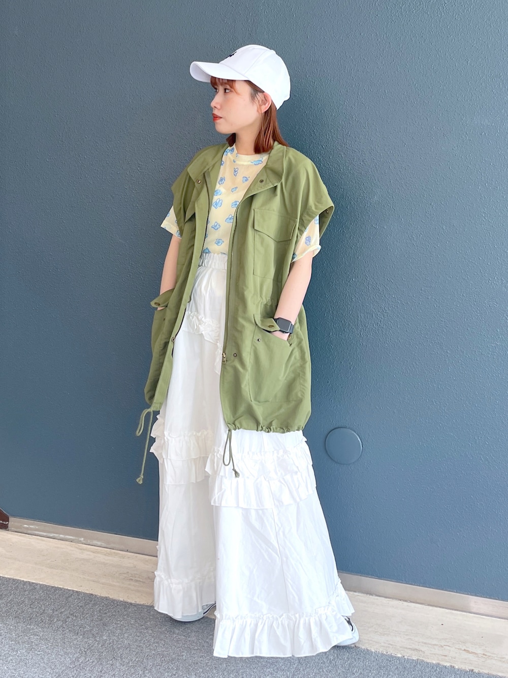 グリーン系のミリタリージャケット、イエロー系のTシャツ/カットソー、ホワイト系のスカートを着用したレディースの春コーディネートの2枚目の写真