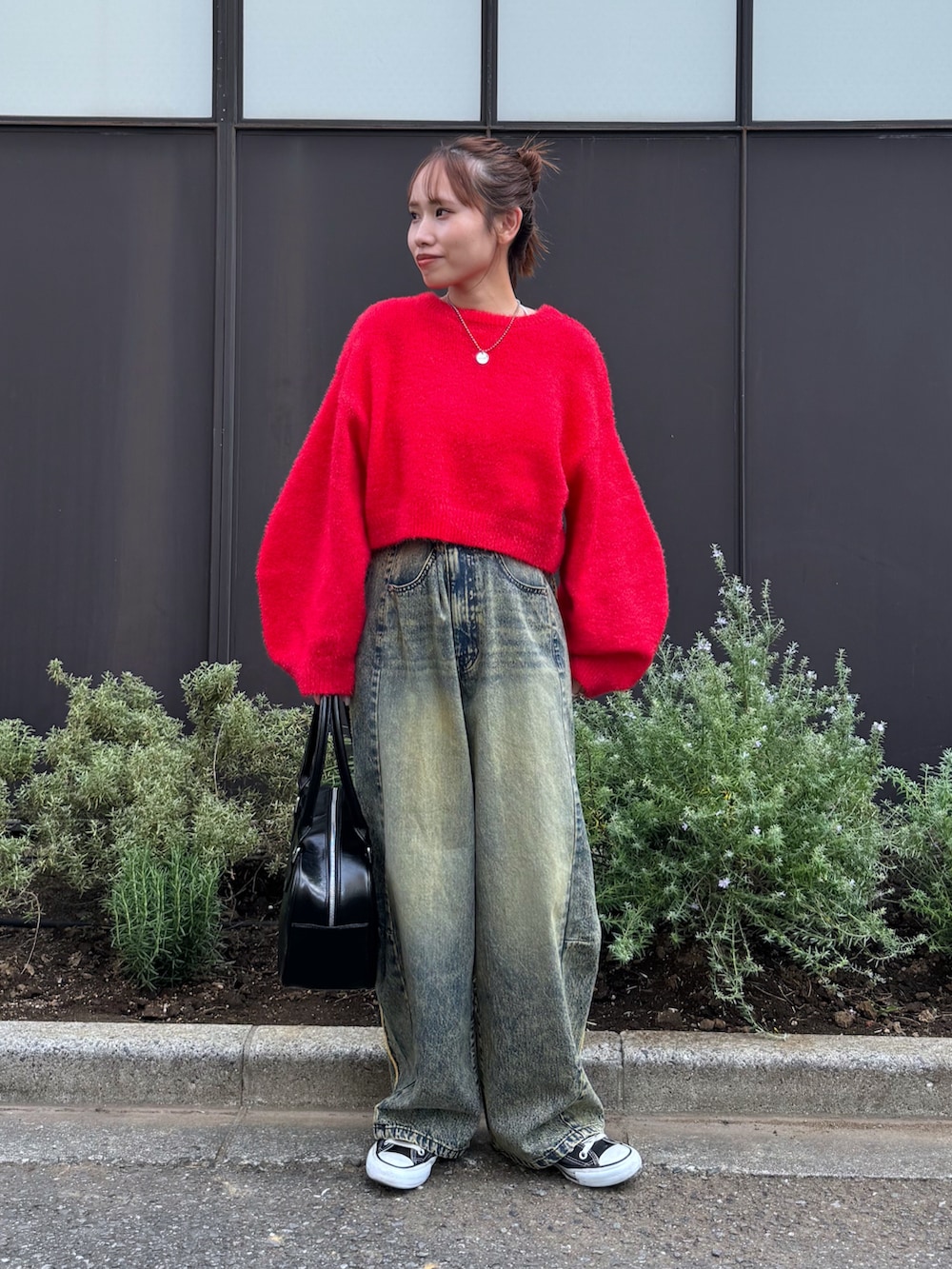 レッド系のニット/セーター、ベージュ系のデニムパンツ、ブラック系のスニーカーを着用したレディースの秋コーディネートの2枚目の写真