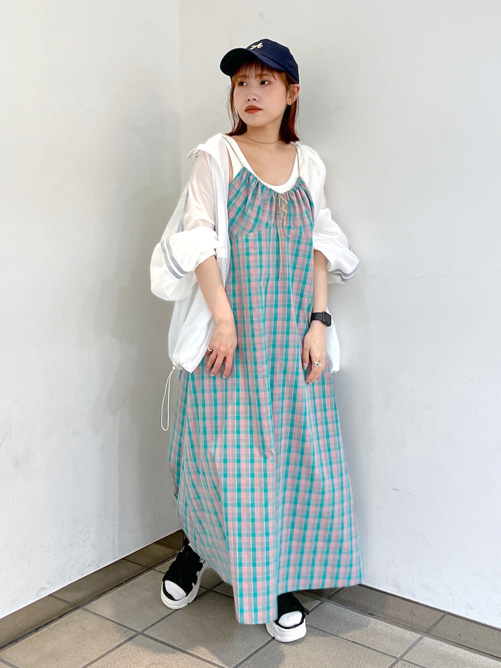 グリーン系のワンピース、ホワイト系のブルゾン、ブラック系のサンダルを着用したレディースの春コーディネートの2枚目の写真