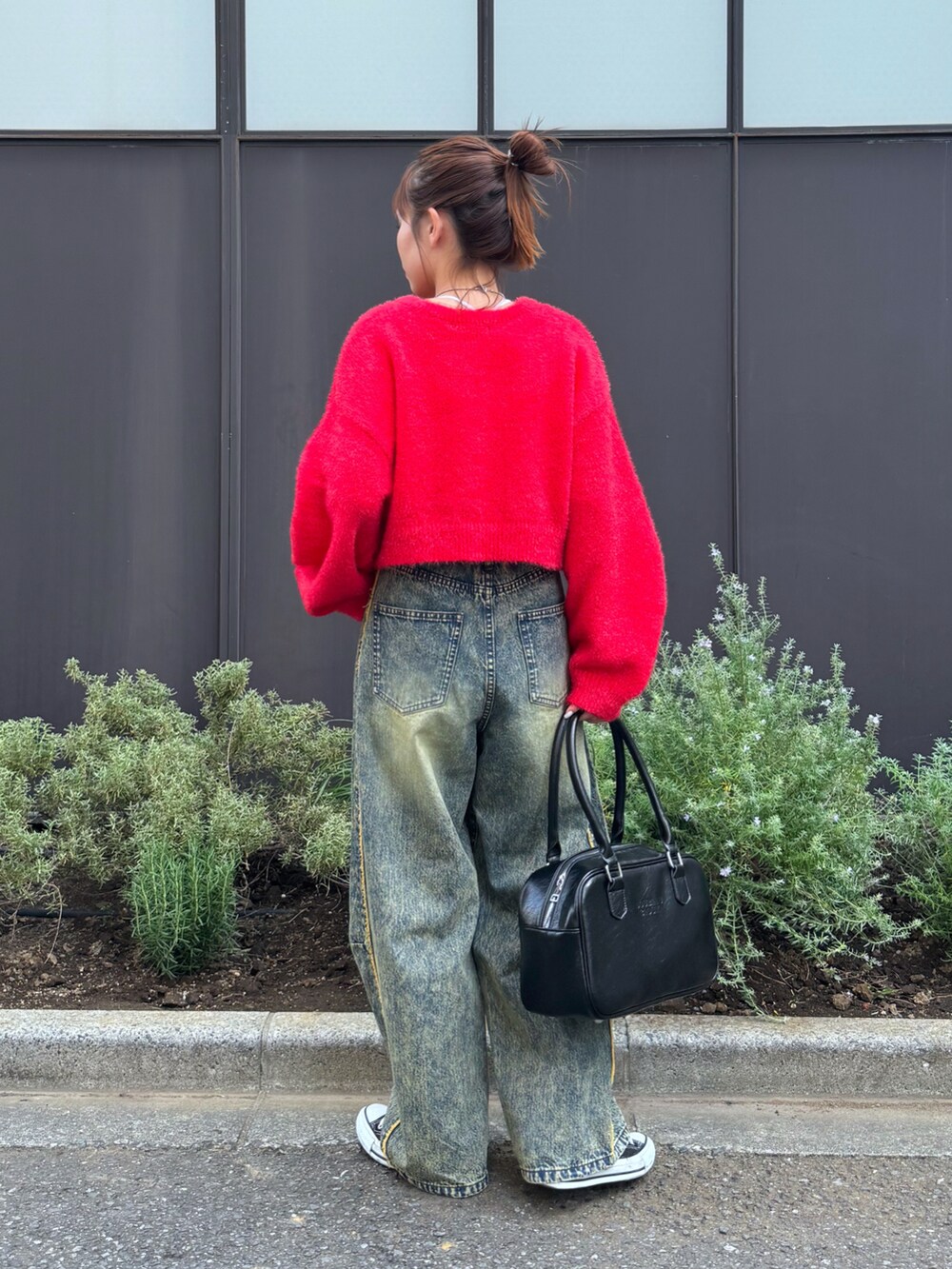 レッド系のニット/セーター、ベージュ系のデニムパンツ、ブラック系のスニーカーを着用したレディースの秋コーディネートの3枚目の写真