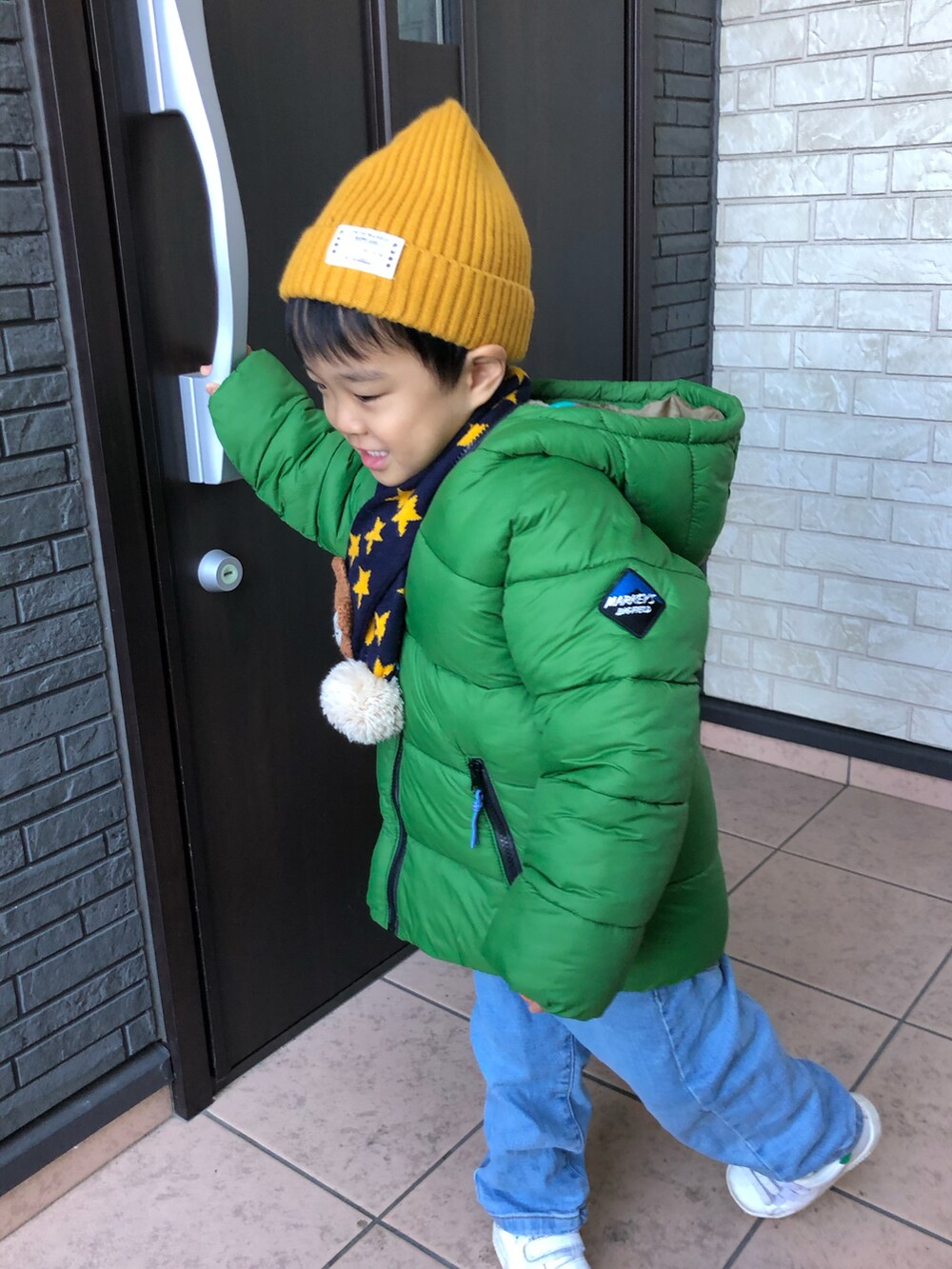 グリーン系のダウンジャケット/コート、ブルー系のデニムパンツ、その他のニット/セーターを着用したキッズの秋コーディネートの3枚目の写真