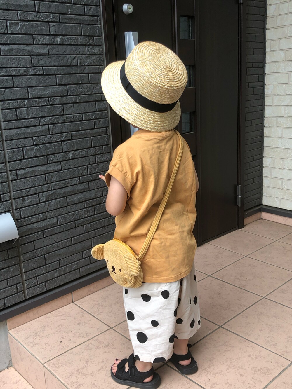 イエロー系のタンクトップ、ベージュ系のその他パンツ、ブラック系のサンダルを着用したキッズの夏コーディネートの3枚目の写真