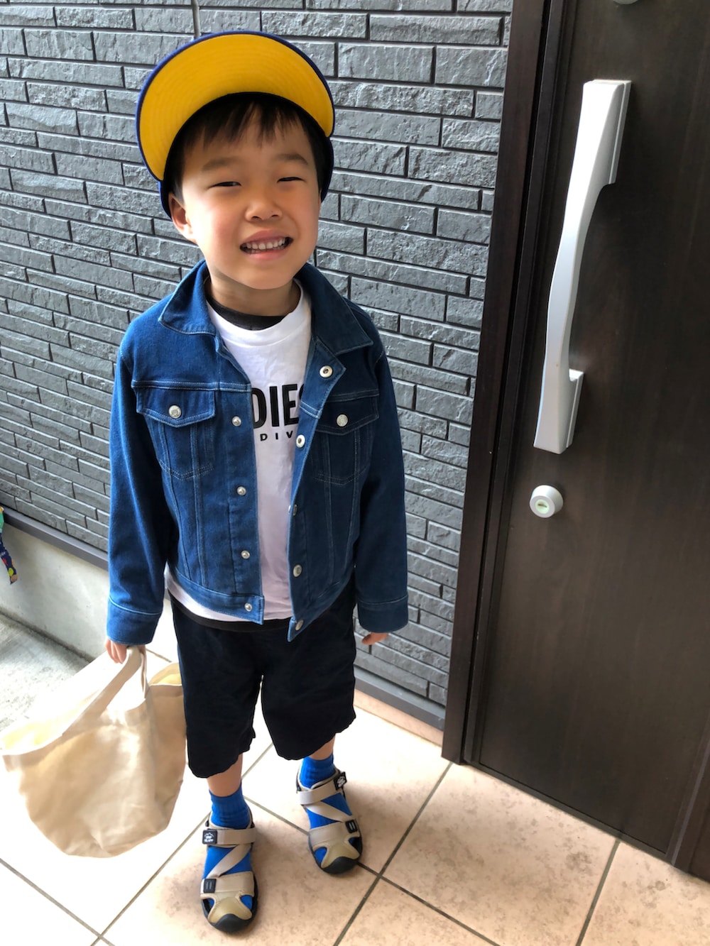 ブルー系のデニムジャケット、ホワイト系のTシャツ/カットソー、ブルー系のキャップを着用したキッズの春コーディネートの3枚目の写真