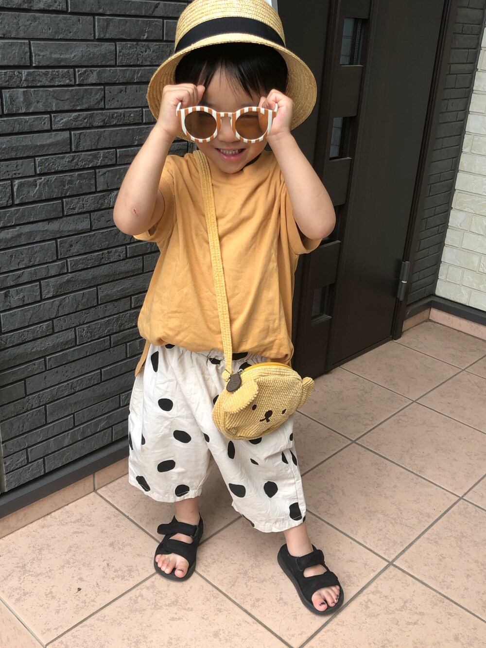 イエロー系のタンクトップ、ベージュ系のその他パンツ、ブラック系のサンダルを着用したキッズの夏コーディネートの2枚目の写真