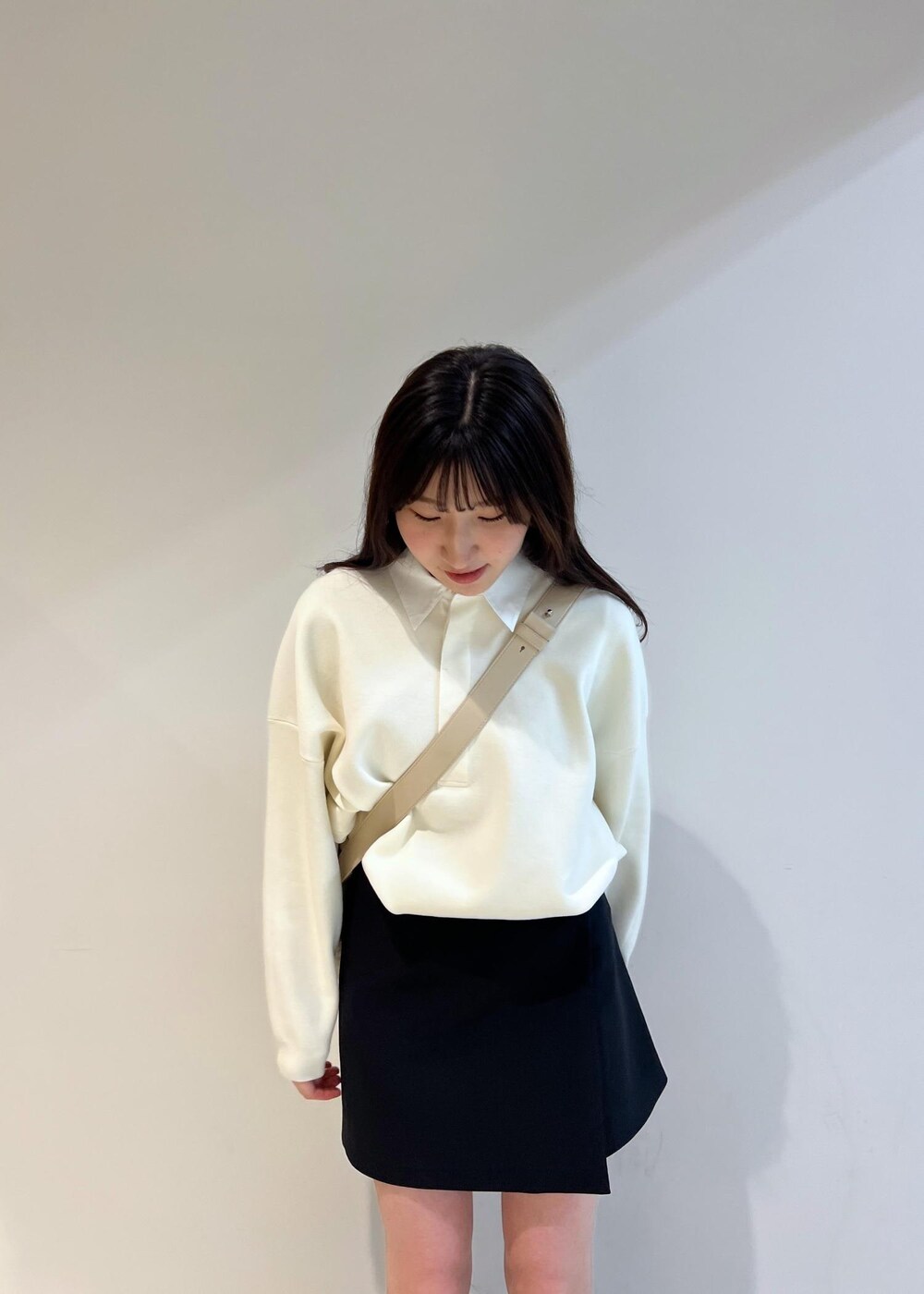 ブラック系のスカート、ベージュ系のショルダーバッグ、ホワイト系のニット/セーターを着用したレディースの冬コーディネートの4枚目の写真