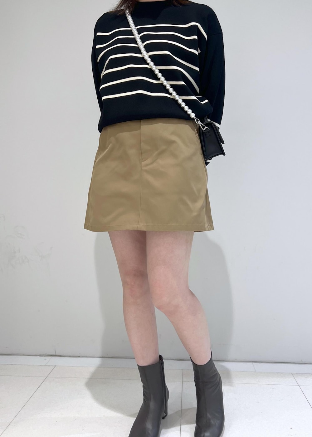 ブラック系のニット/セーター、ブラック系のショルダーバッグ、ベージュ系のスカートを着用したレディースの秋コーディネートの3枚目の写真