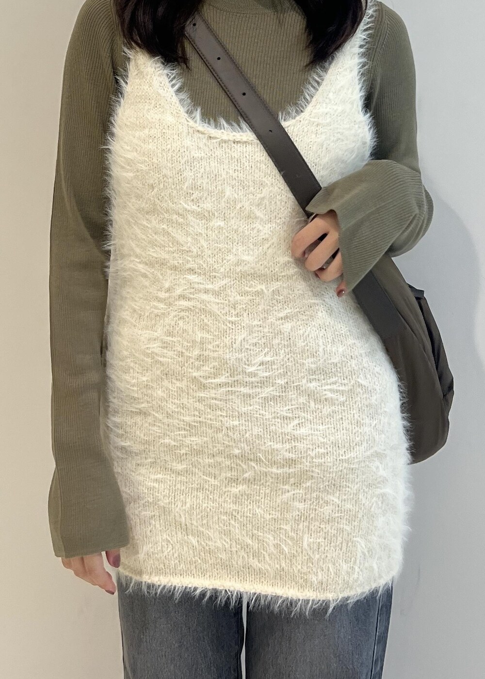 グレー系のデニムパンツ、ブラック系のパンプス、グリーン系のニット/セーターを着用したレディースの秋コーディネートの4枚目の写真